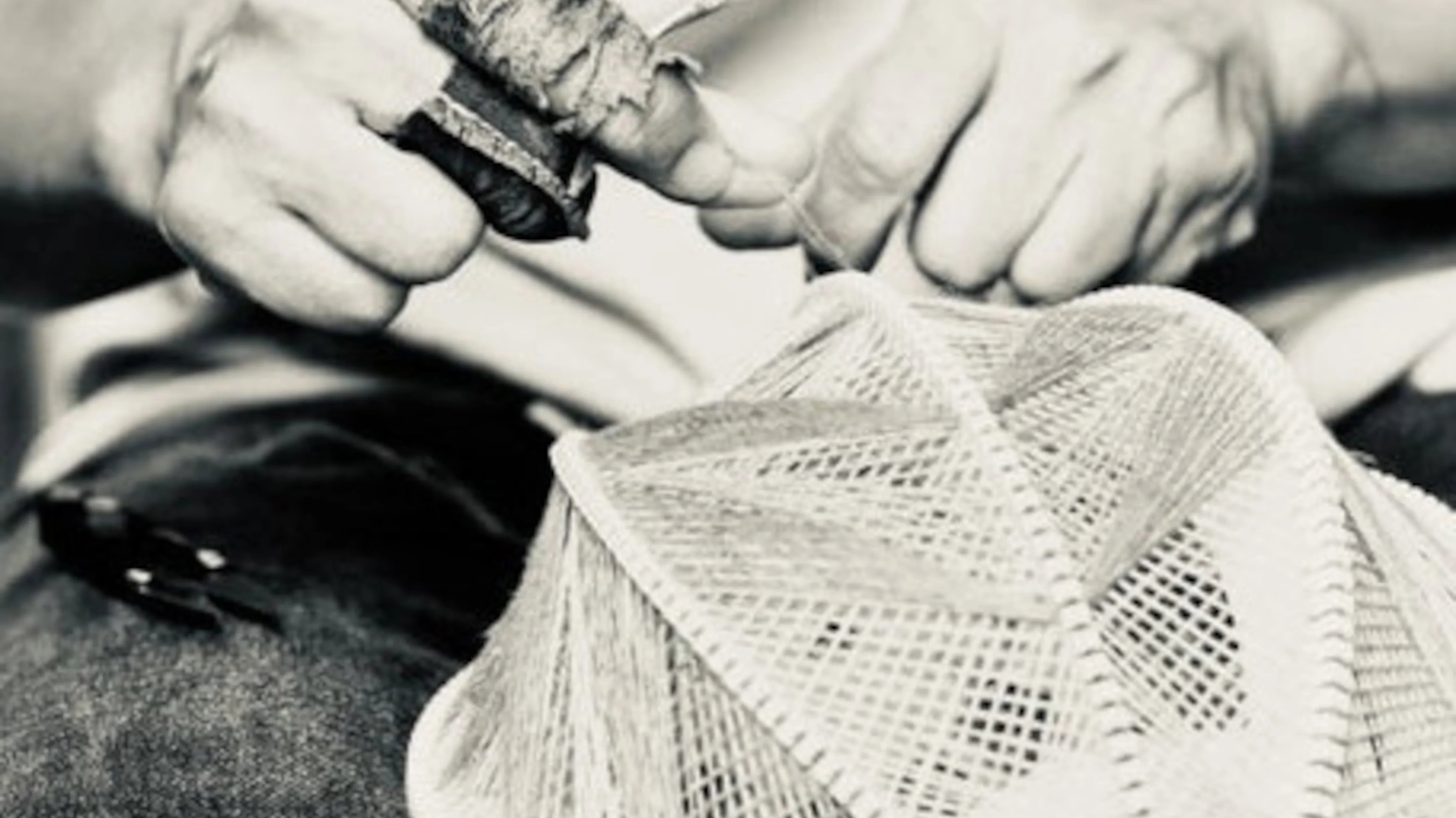 Nahaufnahme von zwei Händen, die einen Lampenschirm weben