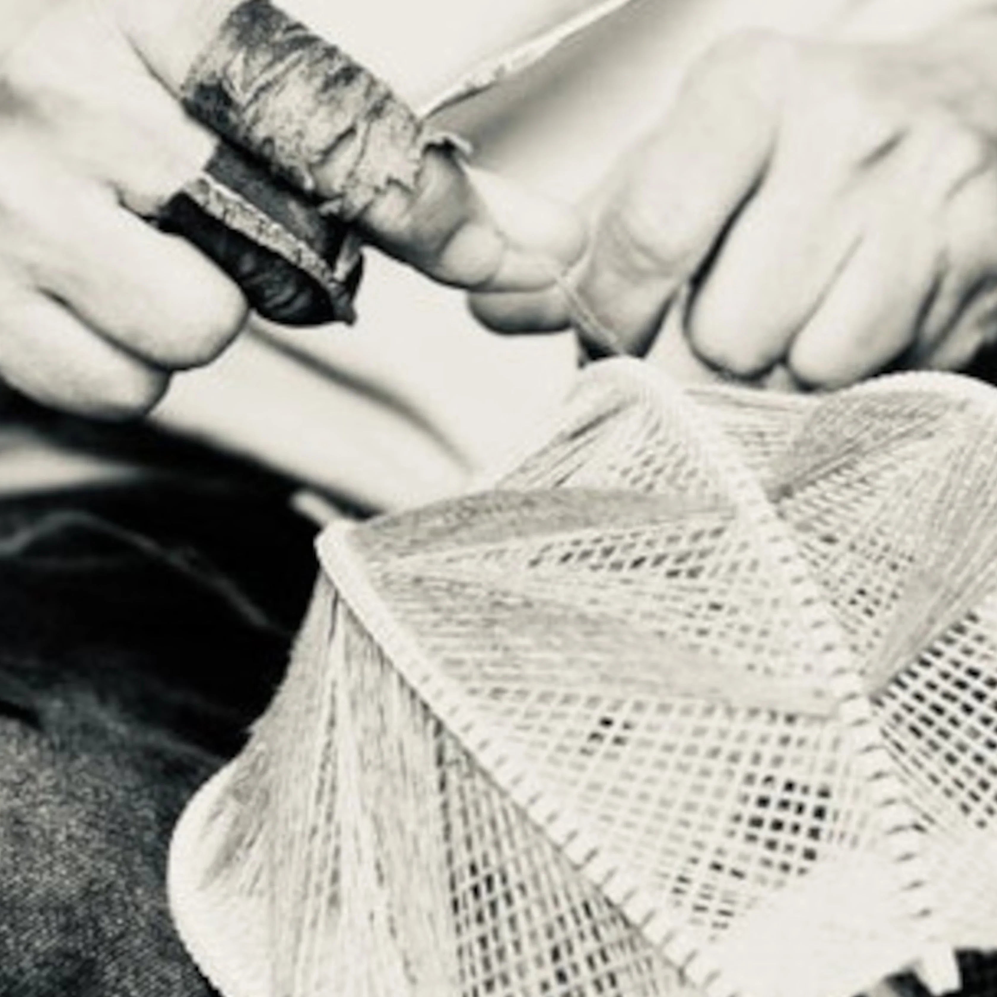 Nahaufnahme von zwei Händen, die einen Lampenschirm weben