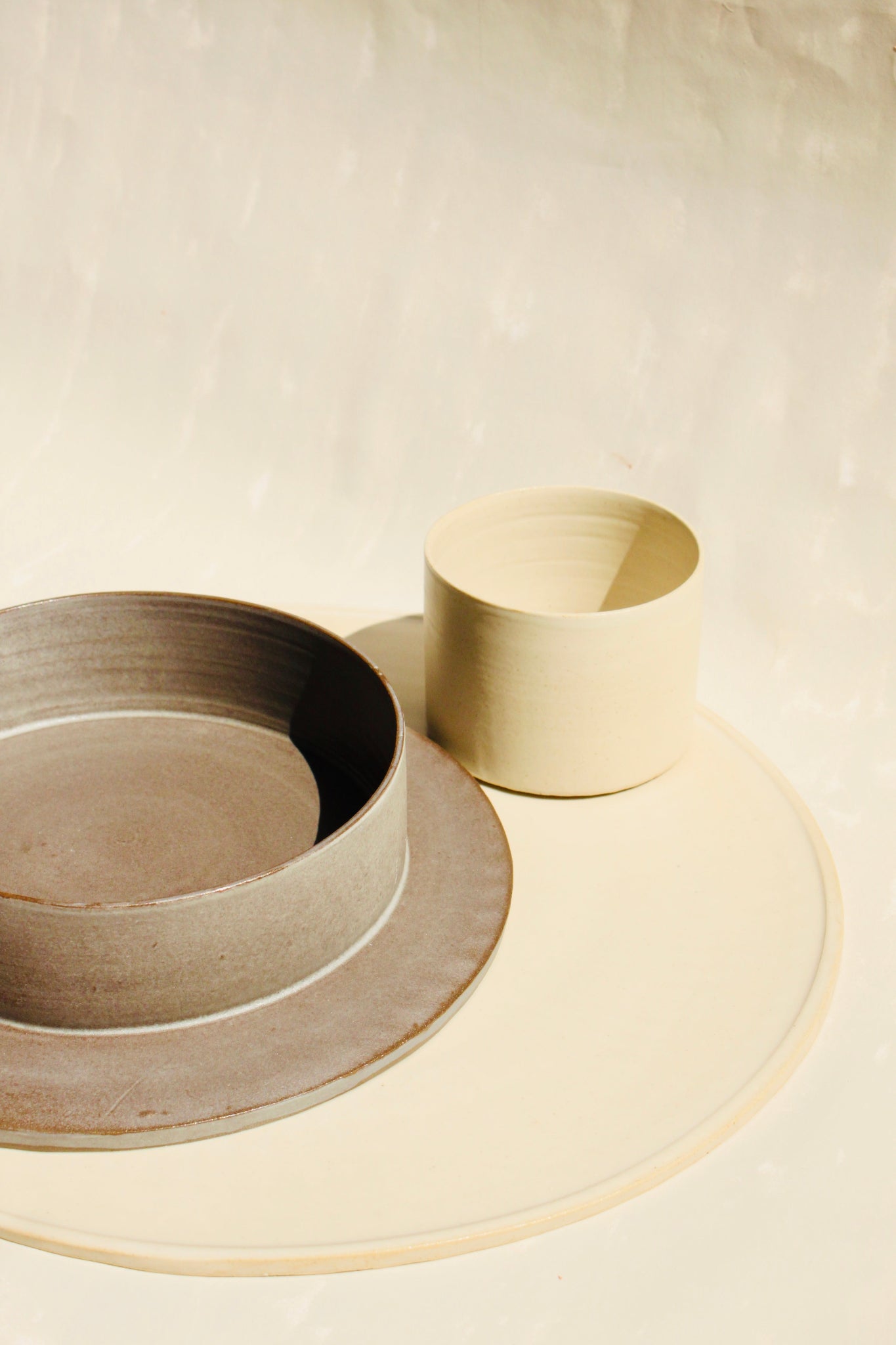 Ein modulares Set der handgefertigten Steingut-Kollektion ROSA MORADA der Genueser Künstlerin Martina Geroni, bestehende aus einem grossemn Pizzateller/Platzset, einem Suppenteller/einer Schale und einem Becher.