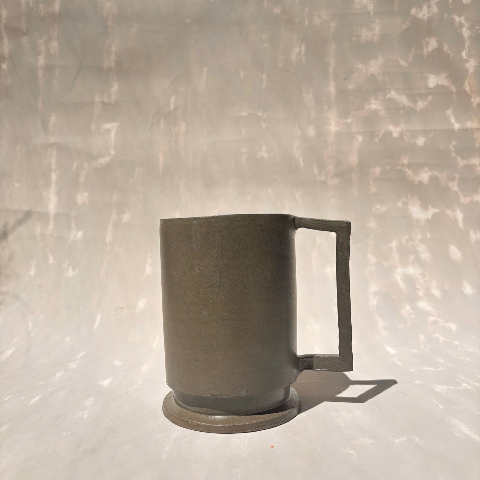 Eine Kermiktasse mit rechteckigem Henkel und Deckel, der zugleich Untersetzer ist, hergestellt von der genueser Künstlerin Martina Geroni.