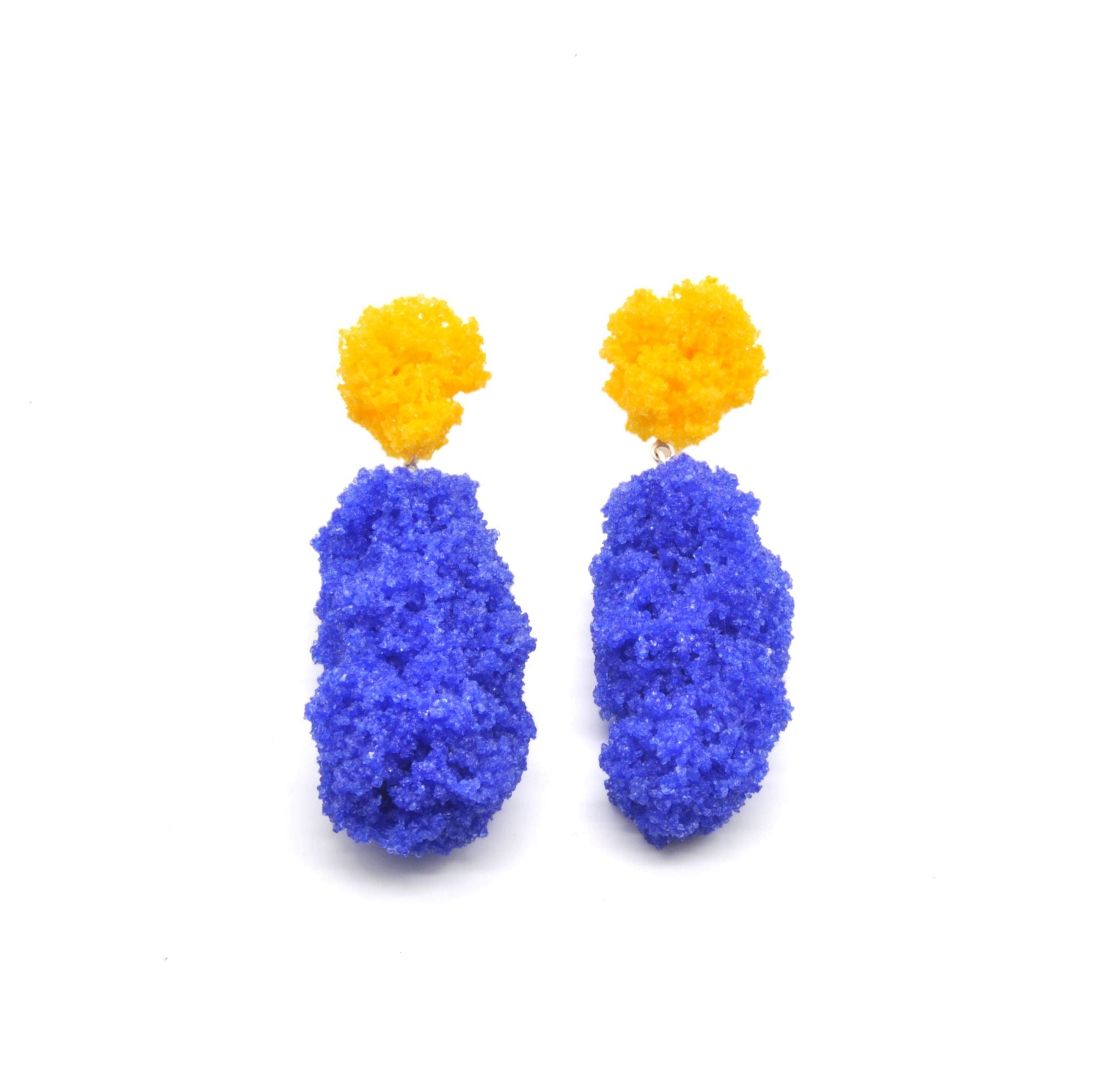 Ein paar Ohrringe aus Zucker und Harz der Künstlerin Carla Movia das obere kleinere Teil ist gelb, das untere grosse Teil ist Oxidblau