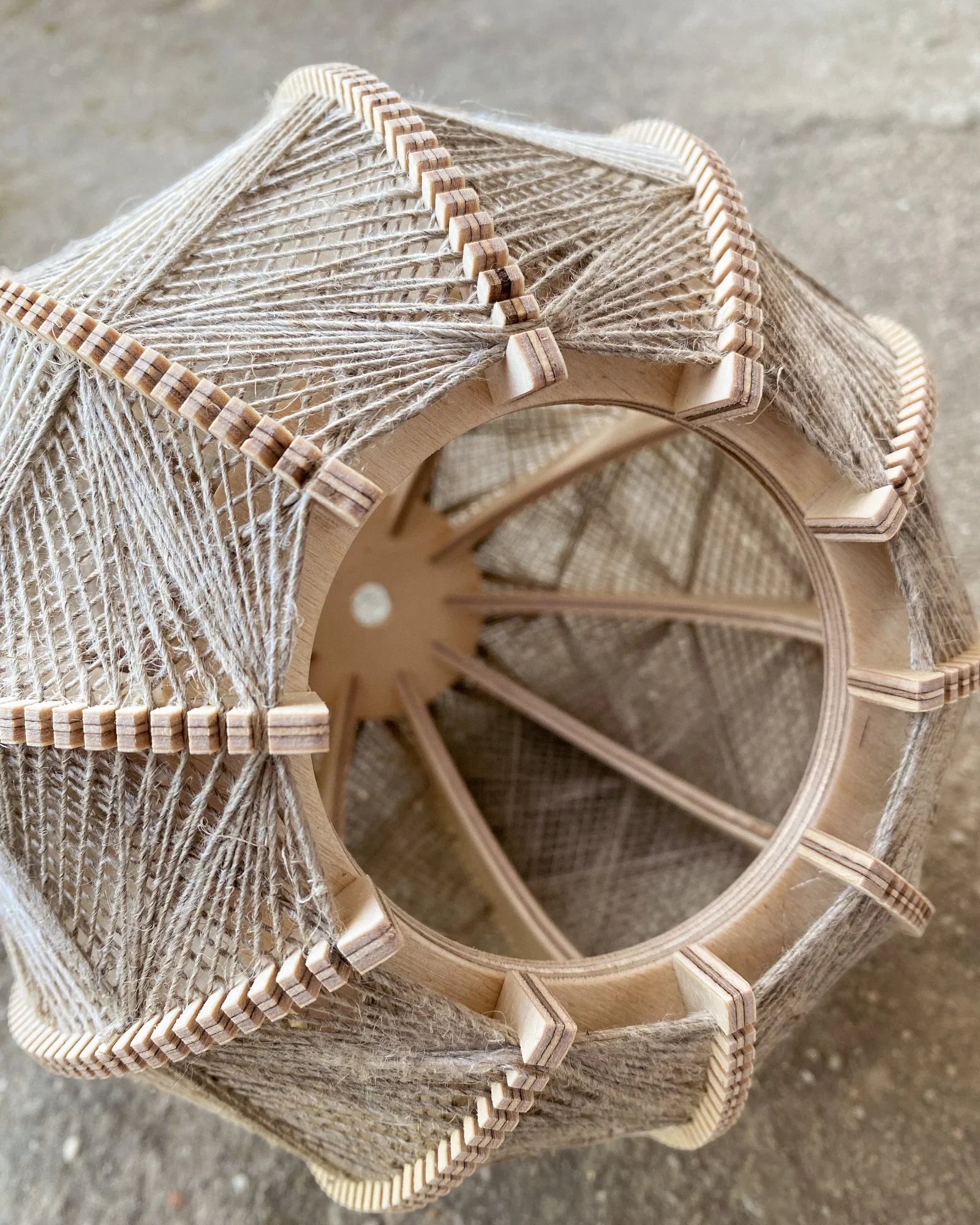 Detailaufnahme ins Innere eines Lampenschirms aus Birkenholz und gewebtem Leinengarn in Beige