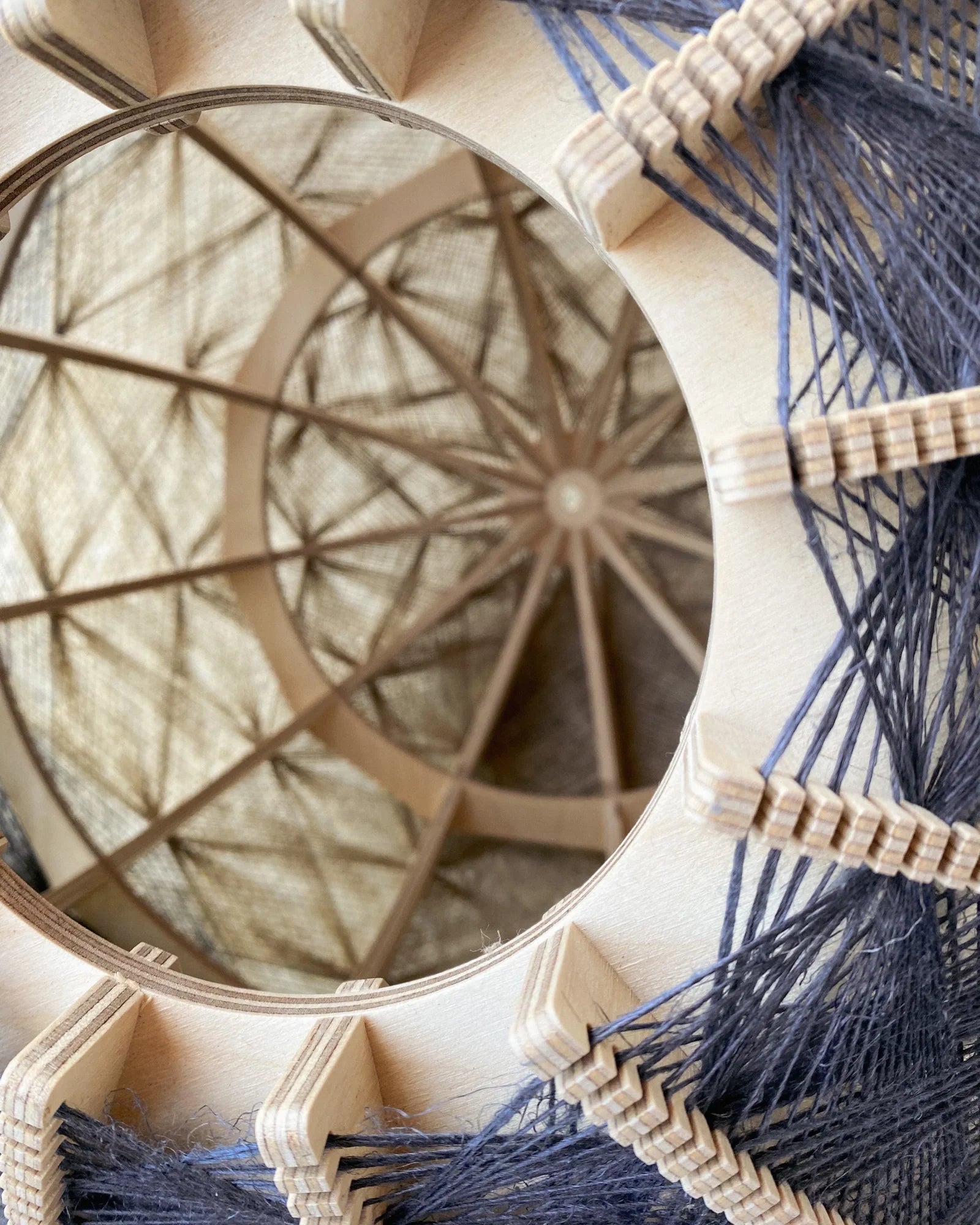 Detailaufnahme ins Innere eines Lampenschirm aus Birkenholz und gewebtem Leinengarn in Beige und Anthrazit