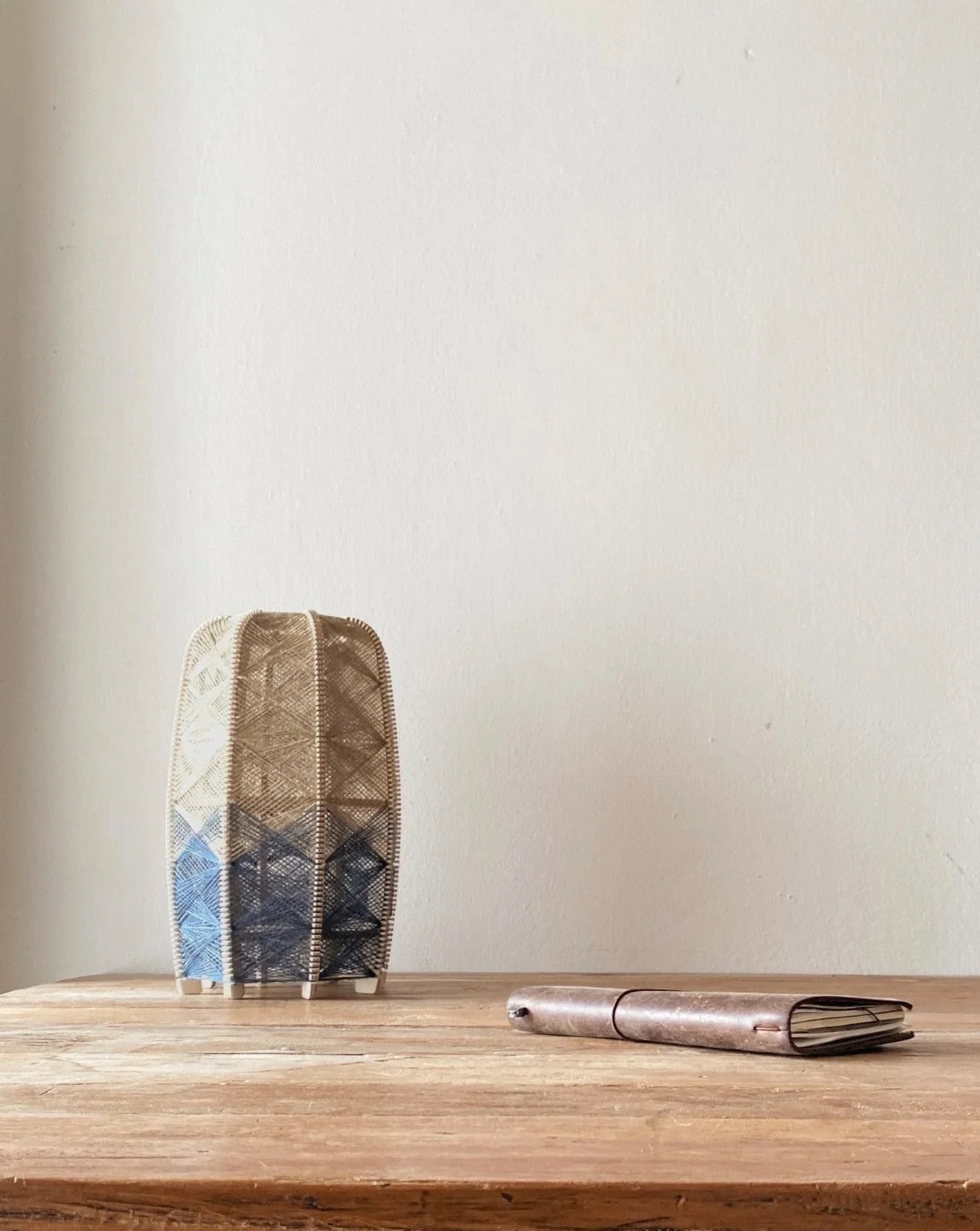 ein gewebter Lampenschirm aus Birkenholz und Leinengarn in Beige und Anthrazit steht auf einem Holztisch