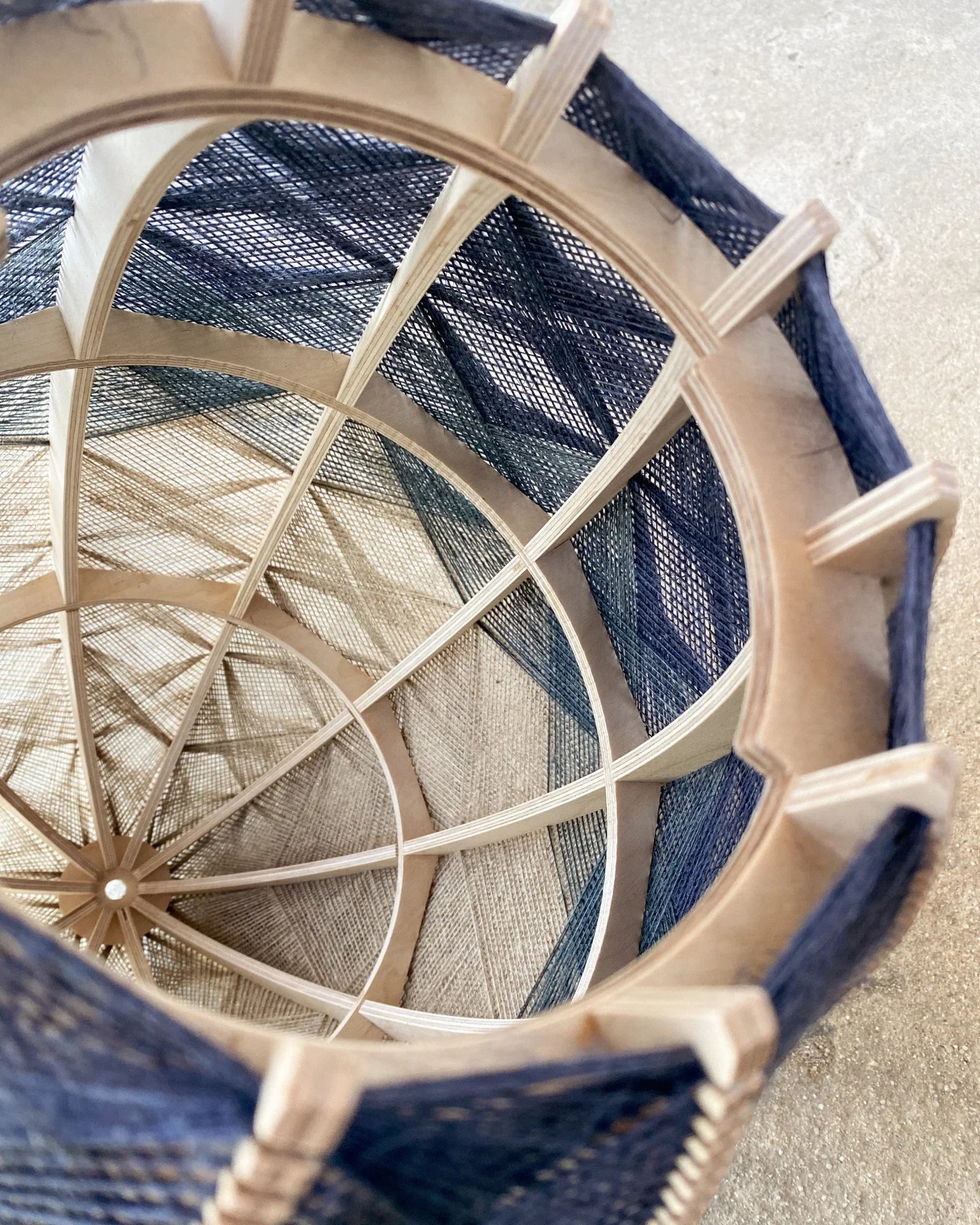 Detailaufnahme des Inneren eines Lampenschirms aus Birkenholzrahmen und zweifarbigem Leinengarn