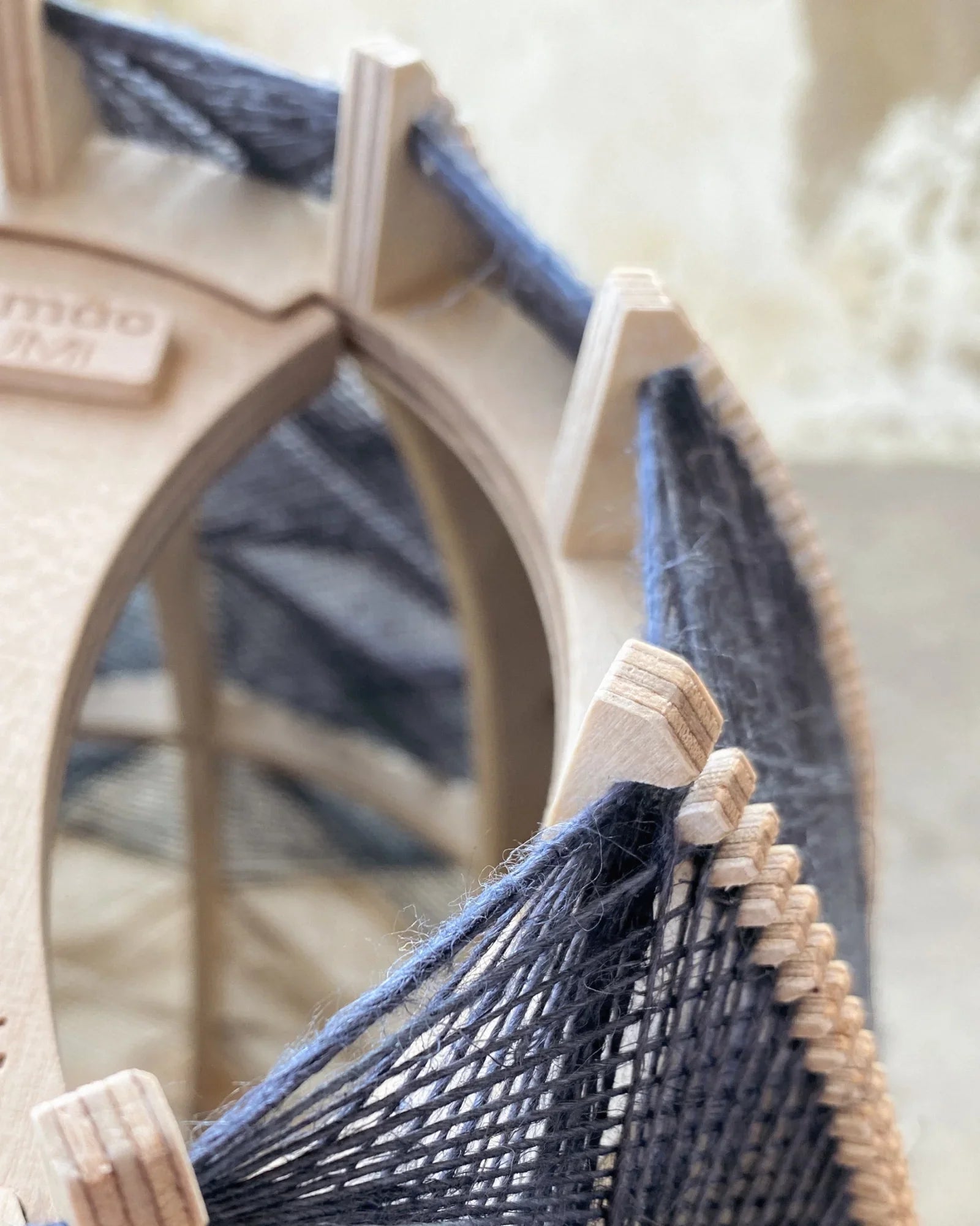 Detailaufnahme eines gewebten Lampenschirms aus Birkenholz und dunklem Leinengarn