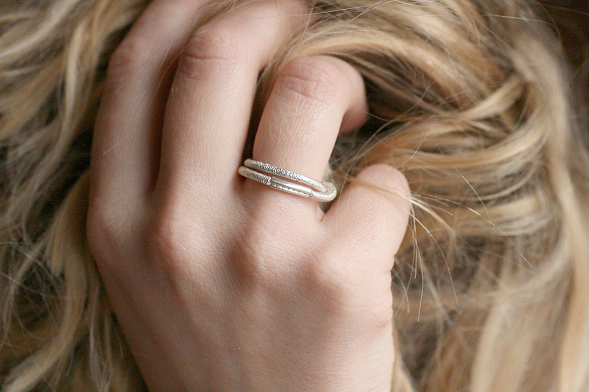 Ein silberner Fingerring, der aussieht wie ein Haargummi, den man sich um den Finger wickelt - gefertigt von der Straßburger Goldschmiedin Annie Sibert.