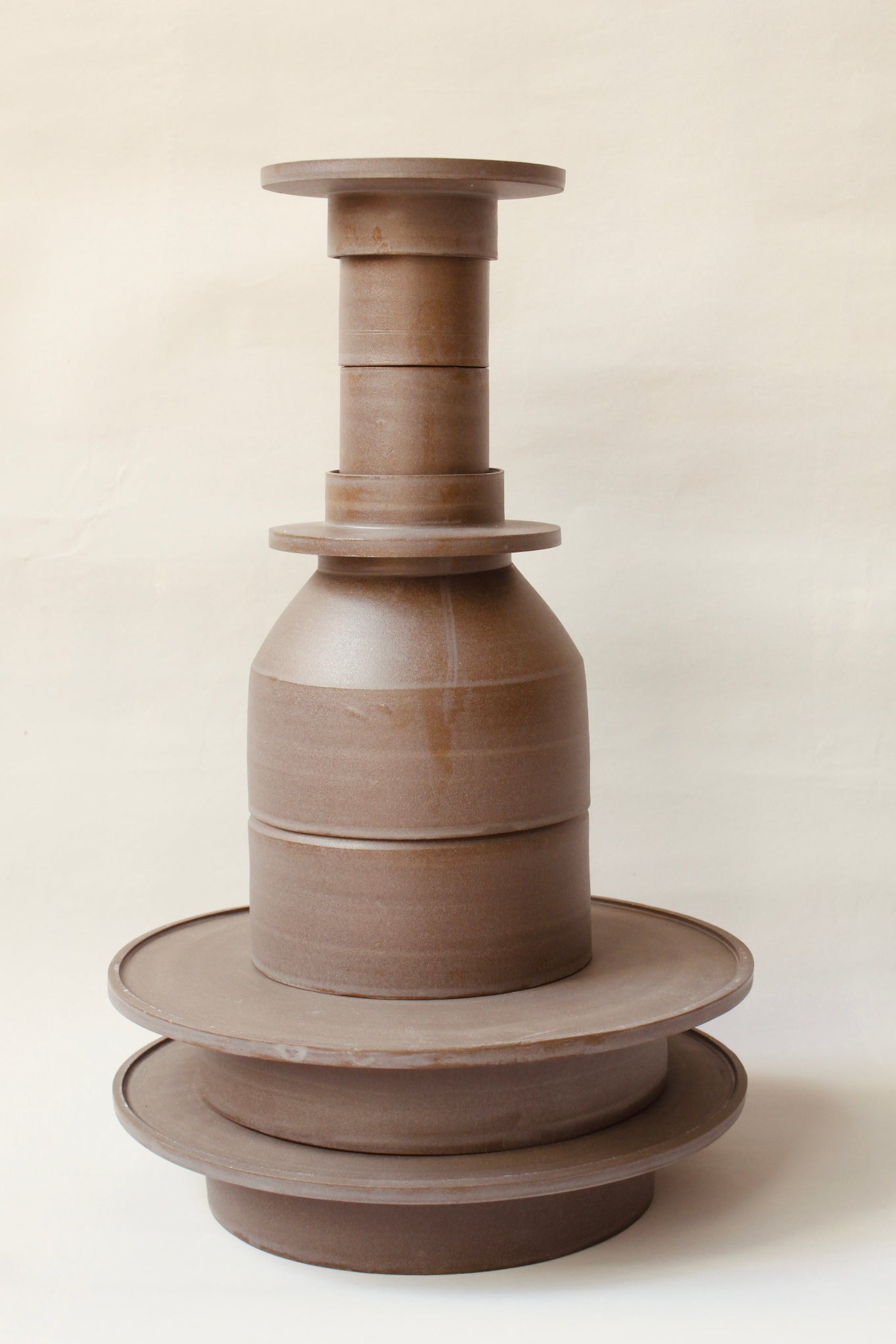 Gestapelte Geschirrskulptur Domenico & Filumena aus der Kollektion ROSA MORADA von Martina Geroni in der Tonfarbe Buccia di Zenzero, bestehend aus zwei Espressobechern mit Schälchen, 2 Schalen und 2 Tellern aus handgefertigtem Steingut.