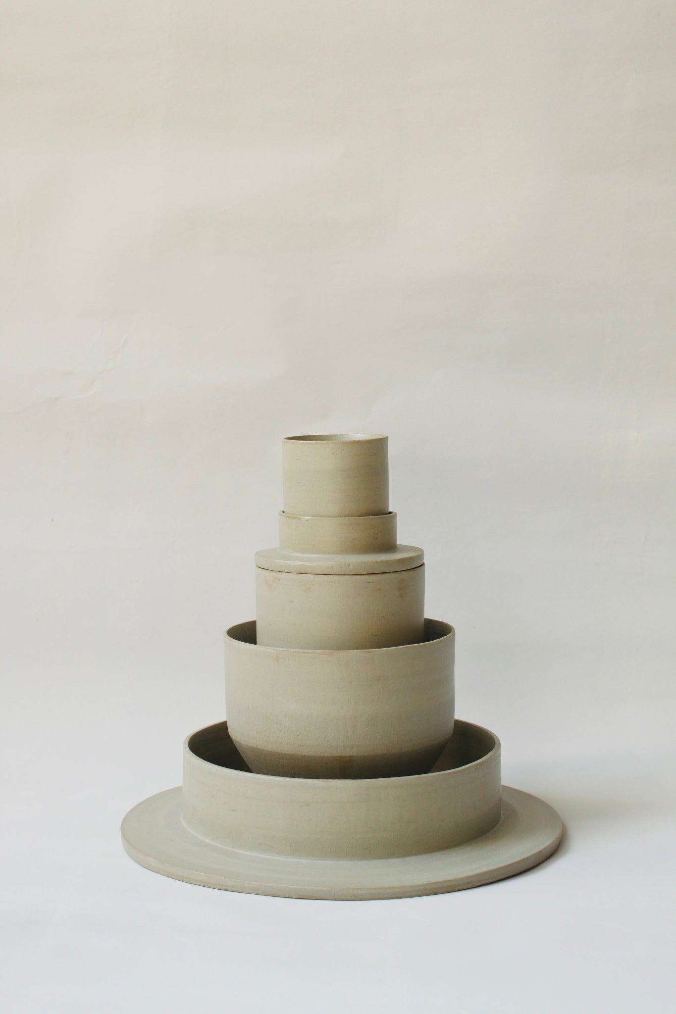 Gestapelte Geschirrskulptur Fefé aus der Kollektion ROSA MORADA von Martina Geroni in der Tonfarbe Salvia, bestehend aus Espressotasse mit Untertasse, Becher, Schale und tiefem Teller aus handgefertigtem Steingut.