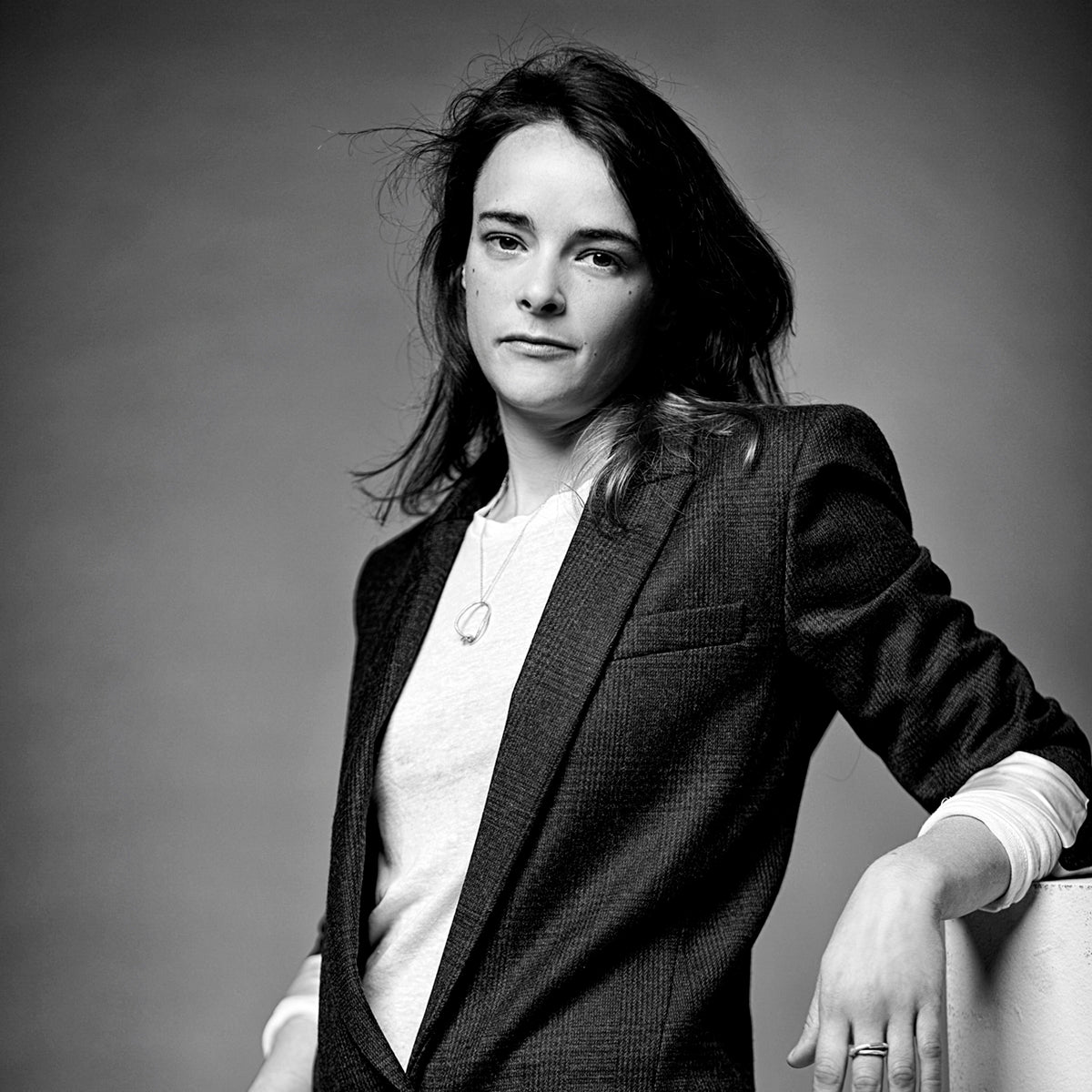 Schwarz-weiss Porträt der Schmuckdesignerin und Gold- und Silberschmiedin Annie Sibert in einem karierten Jacket.