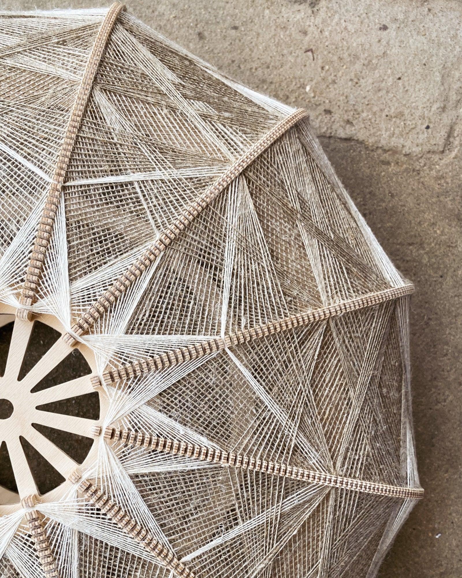 Detailaufnahme des Rahmens und Webmusters eines Lampenschirms aus Birkenholz und beigem Leinengarn