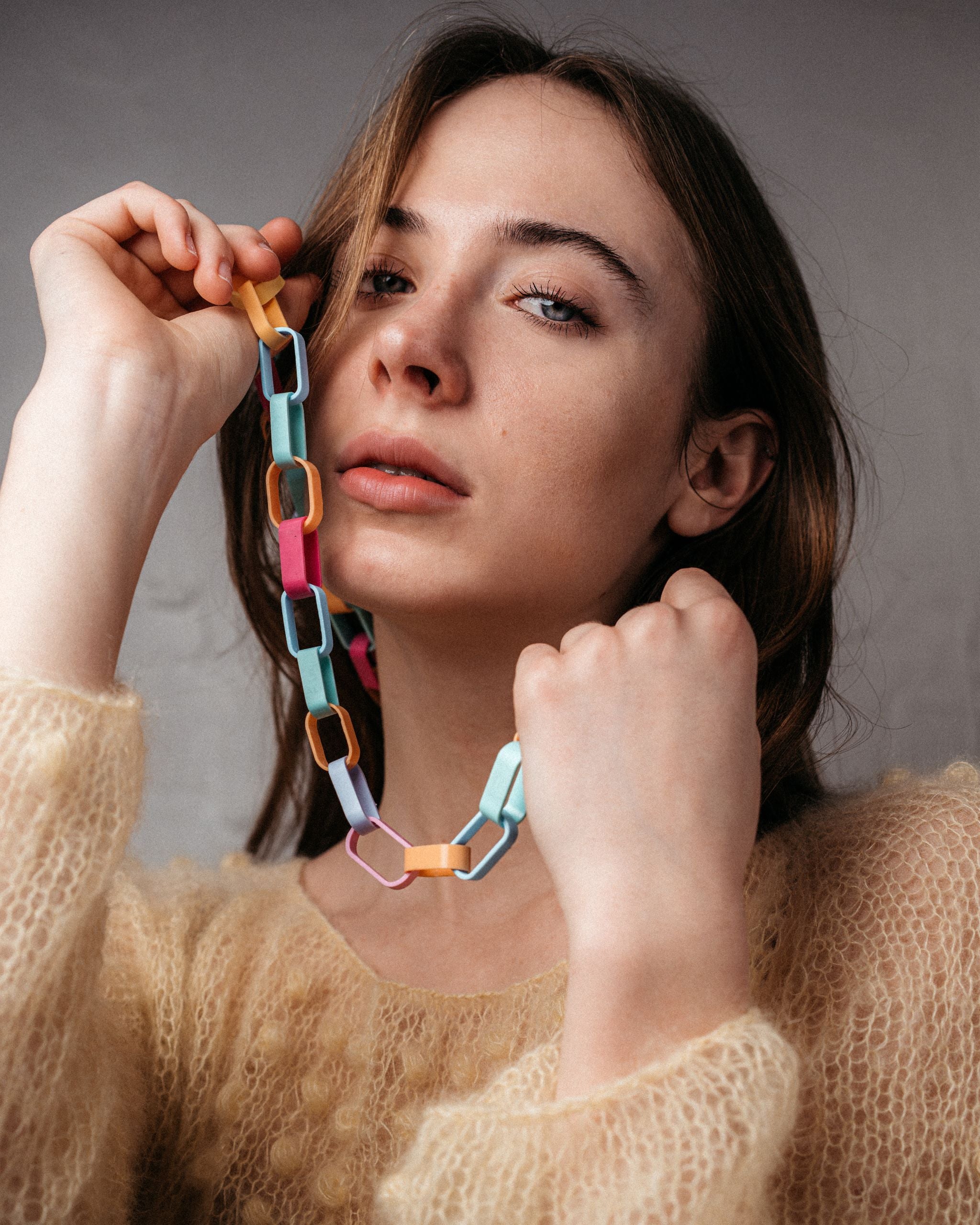 Ein Model trägt eine Gliederkette der Schmuckdesignerin Carla Movia, deren große Glieder in pastelligen, aber kräftigen Farben aus recyclten Hülsen von Textmarkern bestehen.