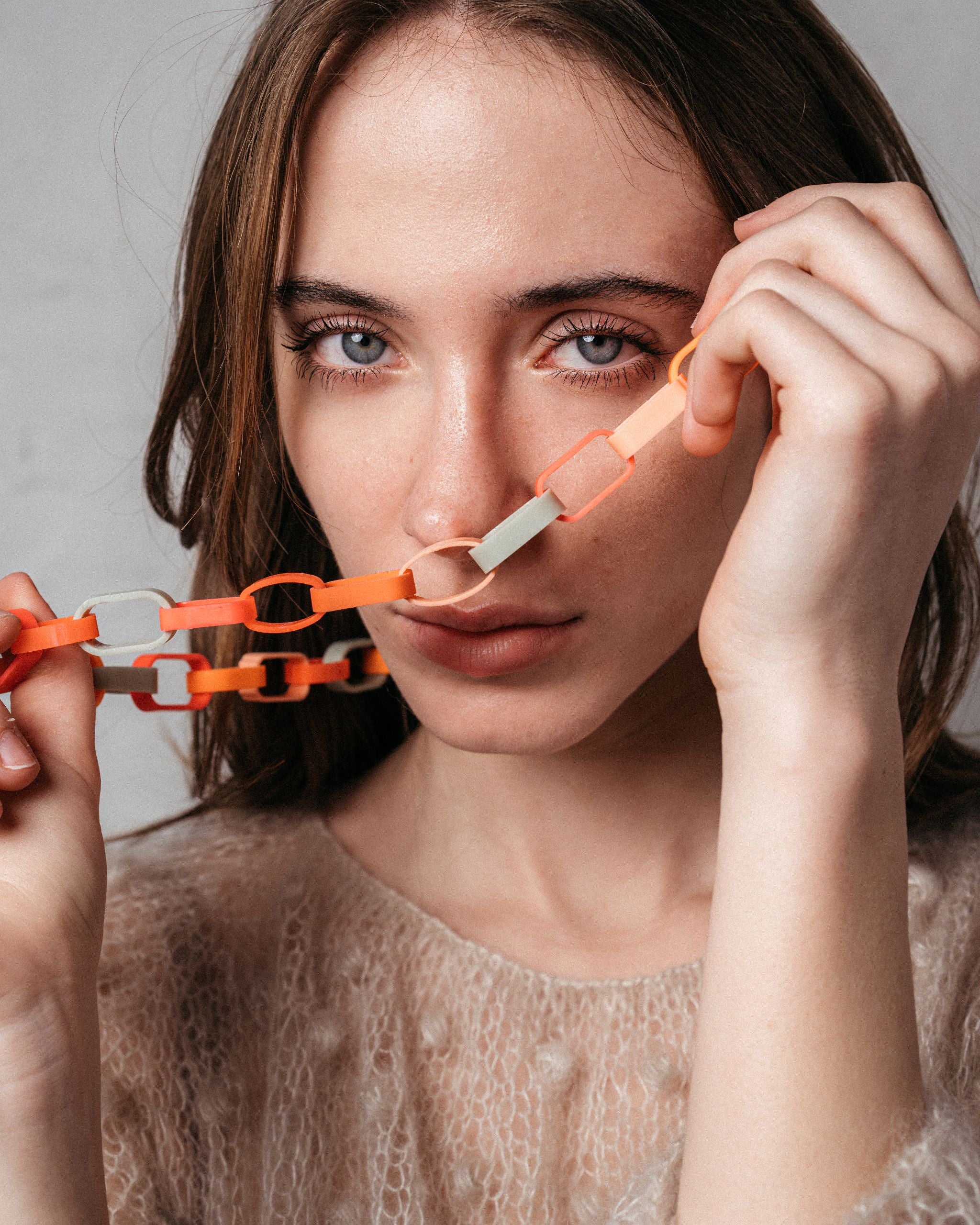 Ein Model trägt eine Gliederkette der Schmuckdesignerin Carla Movia, deren große Glieder in herbstlich leuchtenden Farben aus recyclten Hülsen von Textmarkern bestehen.