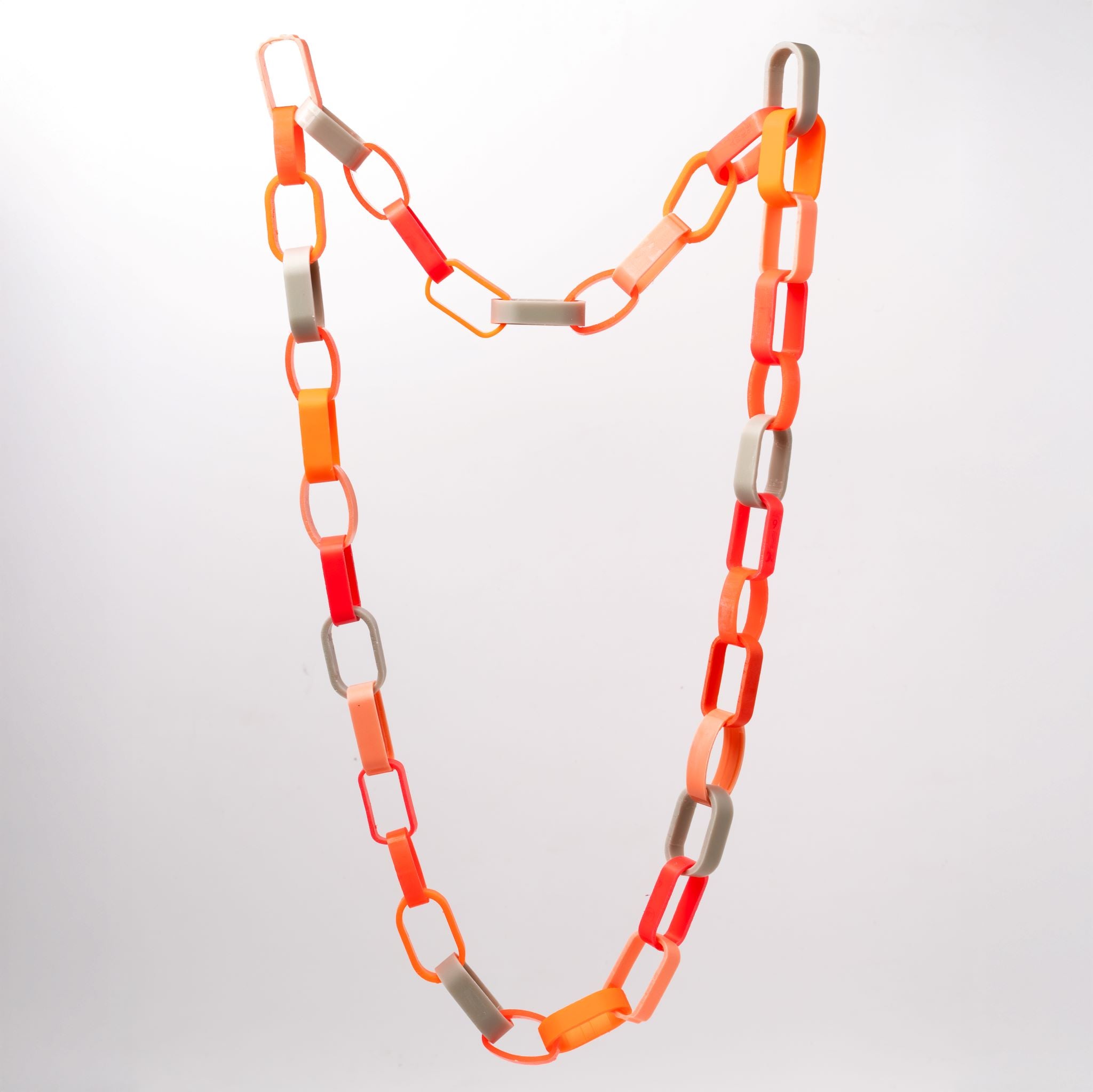 Komplettaufnahme einer Gliederkette der Schmuckdesignerin Carla Movia, deren große Glieder in herbstlich leuchtenden Farben aus recyclten Hülsen von Textmarkern bestehen.