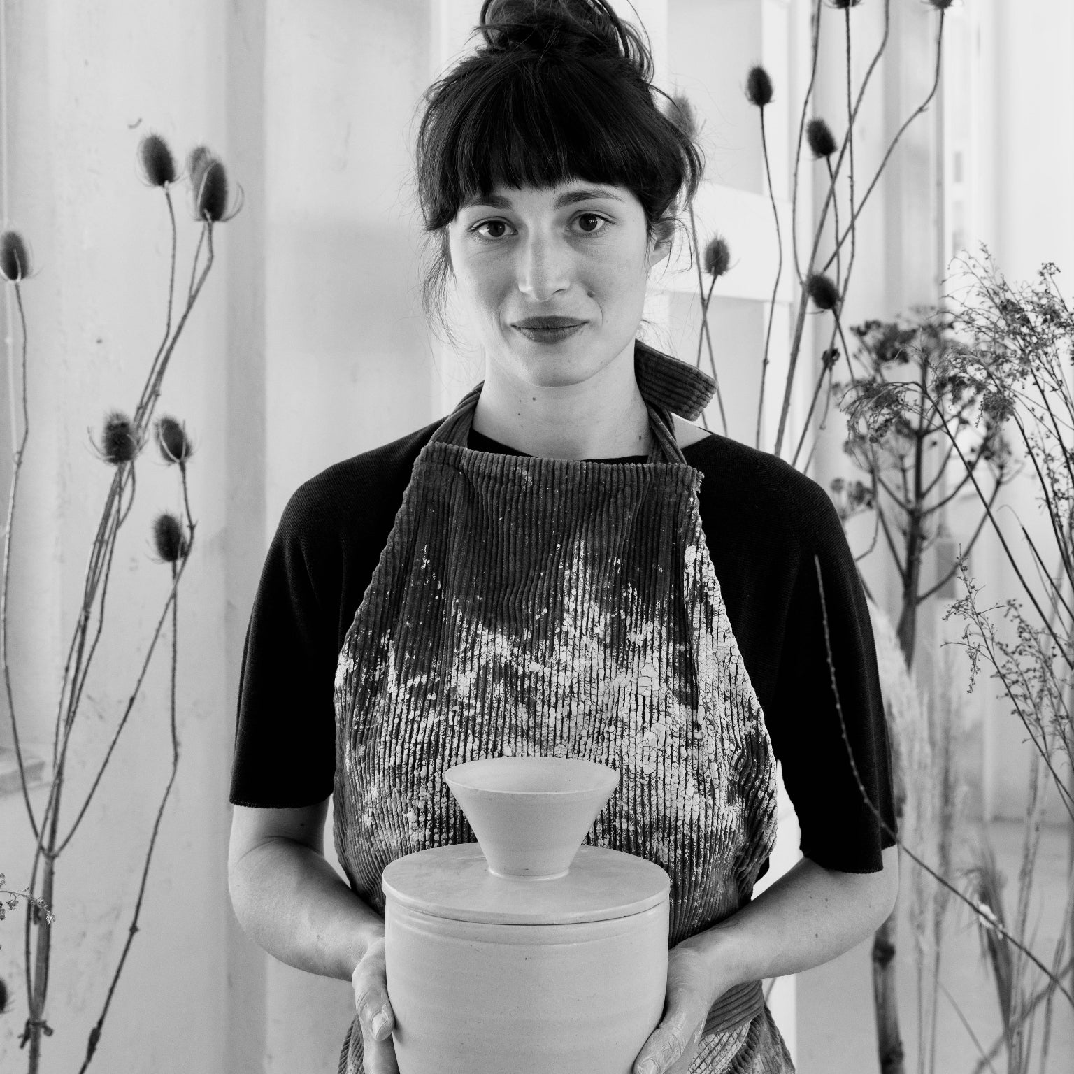 Porträt der Keramikkünstlerin Martina Geroni mit Schürze und einem handgefertigten Riccotatopf in der Hand. Credit: Federica Cocciro