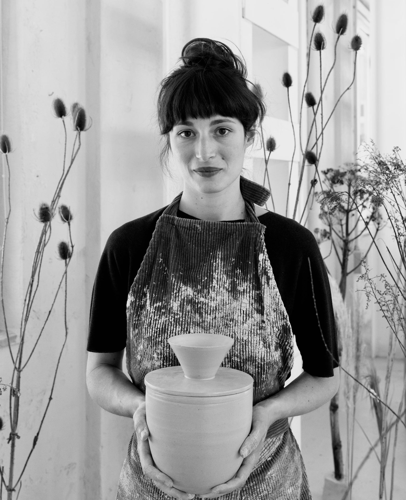 Porträt der Keramikkünstlerin Martina Geroni mit Schürze und einem handgefertigten Riccotatopf in der Hand. Credit: Federica Cocciro