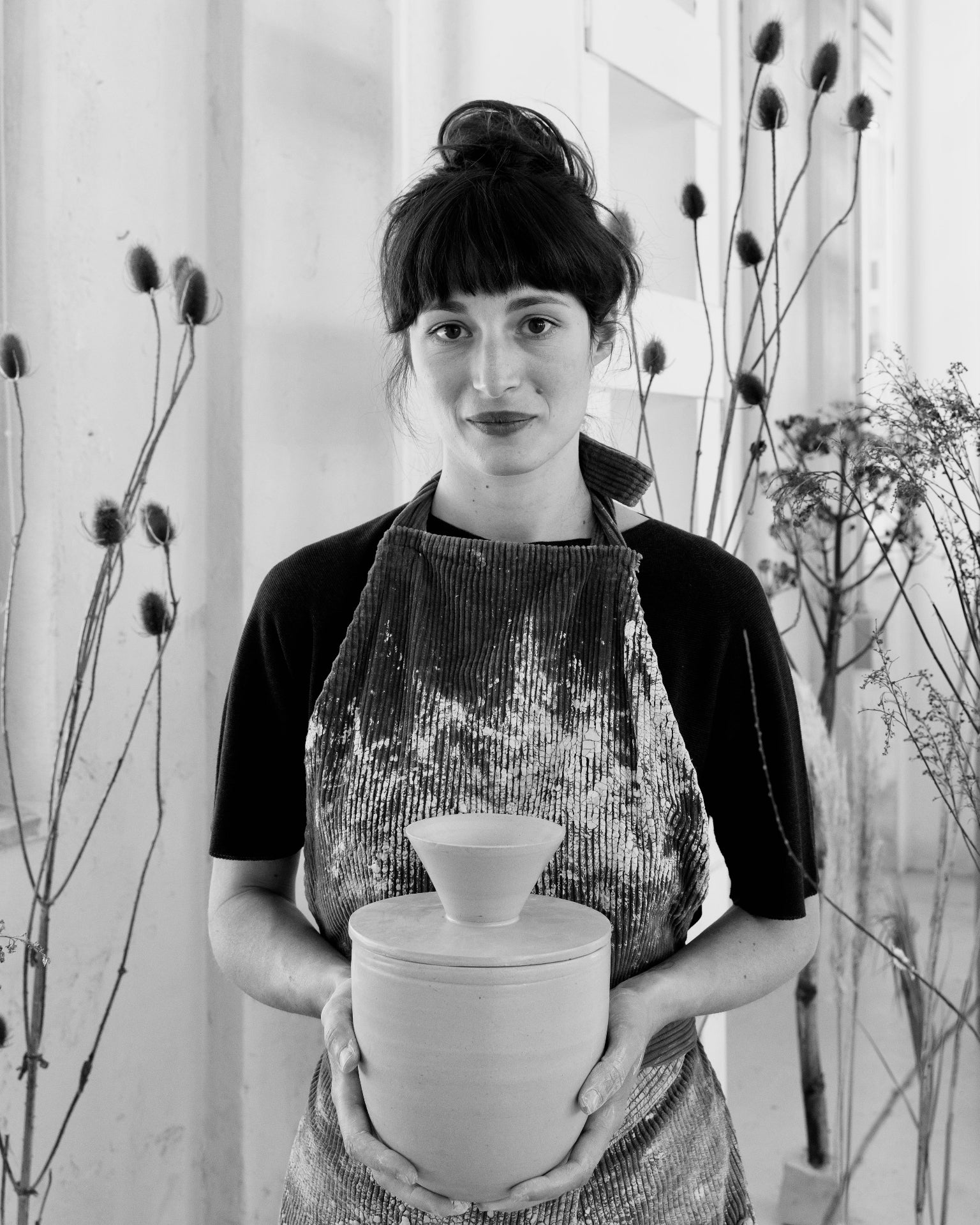 Porträt der Keramikkünstlerin Martina Geroni mit Schürze und einem handgefertigten Riccotatopf in der Hand. Credit: Federica Cocciro