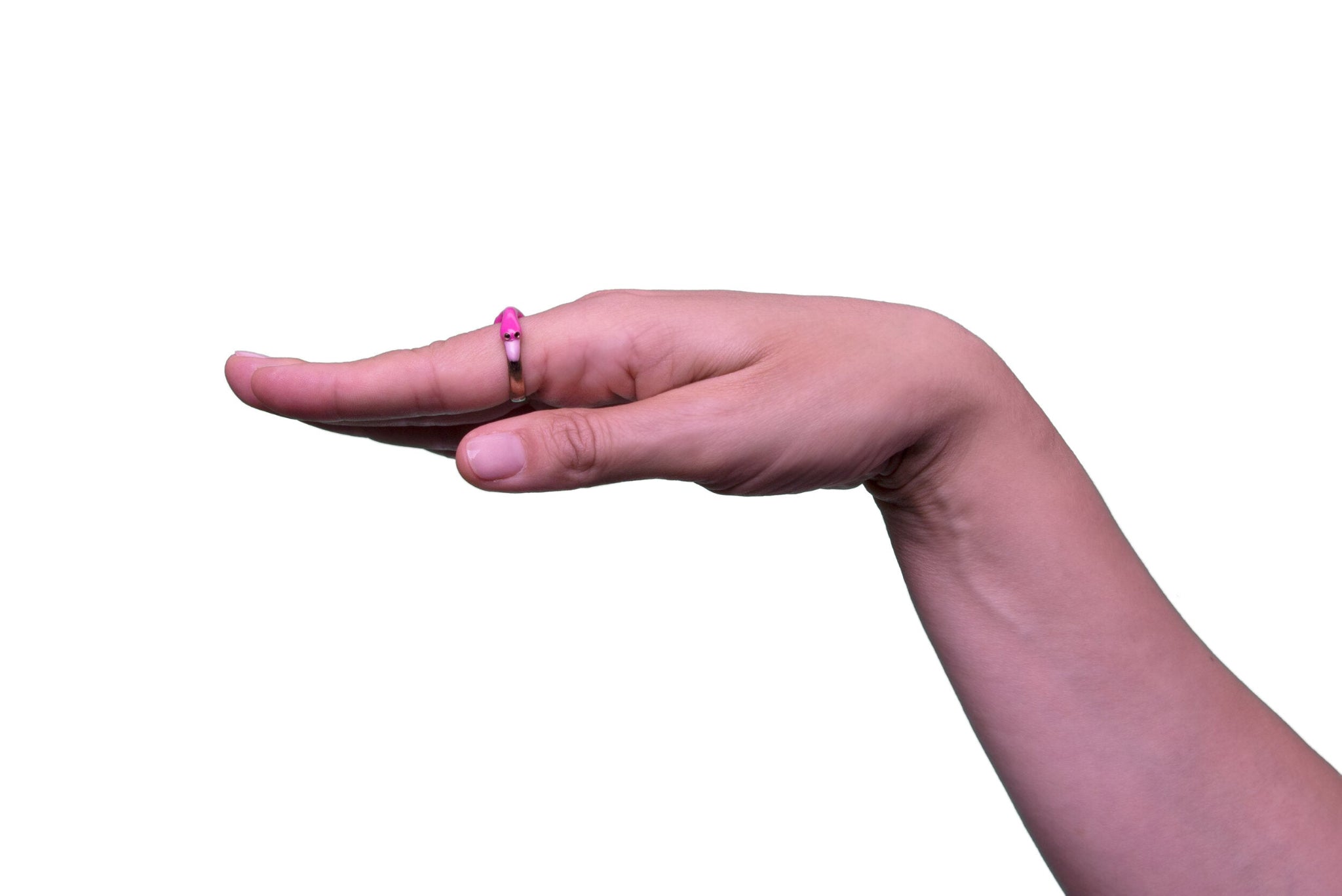 Eine Hand trögt am Zeigefinger einen Ring der italienischen Schmuckdesignerin Chiara Bello in Form eines pinken Flamingos mir rosa Schnabel, goldenen Konturen und schwarzen Steinchen als Augen - Seitenansicht.