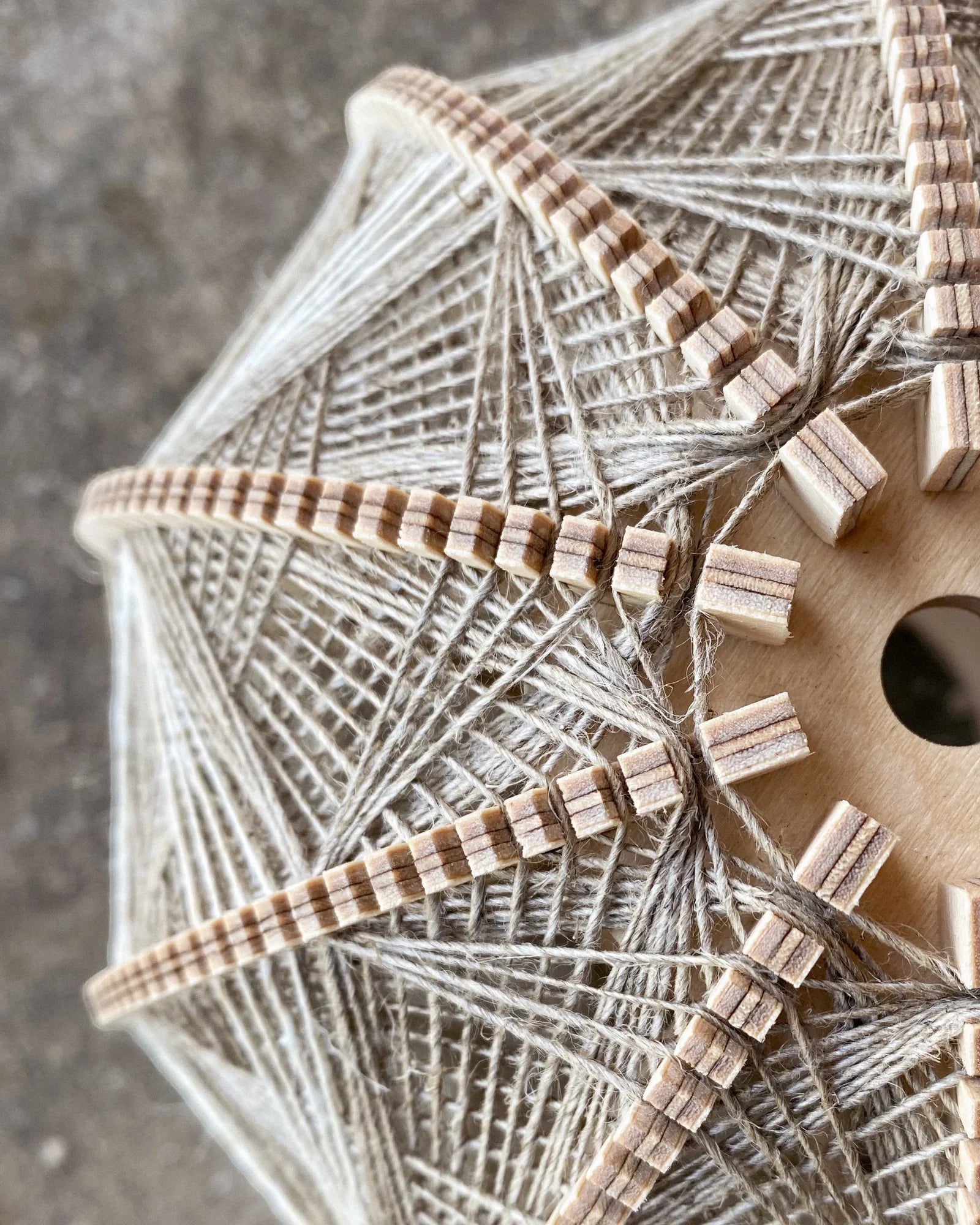 Detailaufnahme des Rahmens und Webmusters eines Lampenschirm aus Birkenholz und Leinengarn in Beige