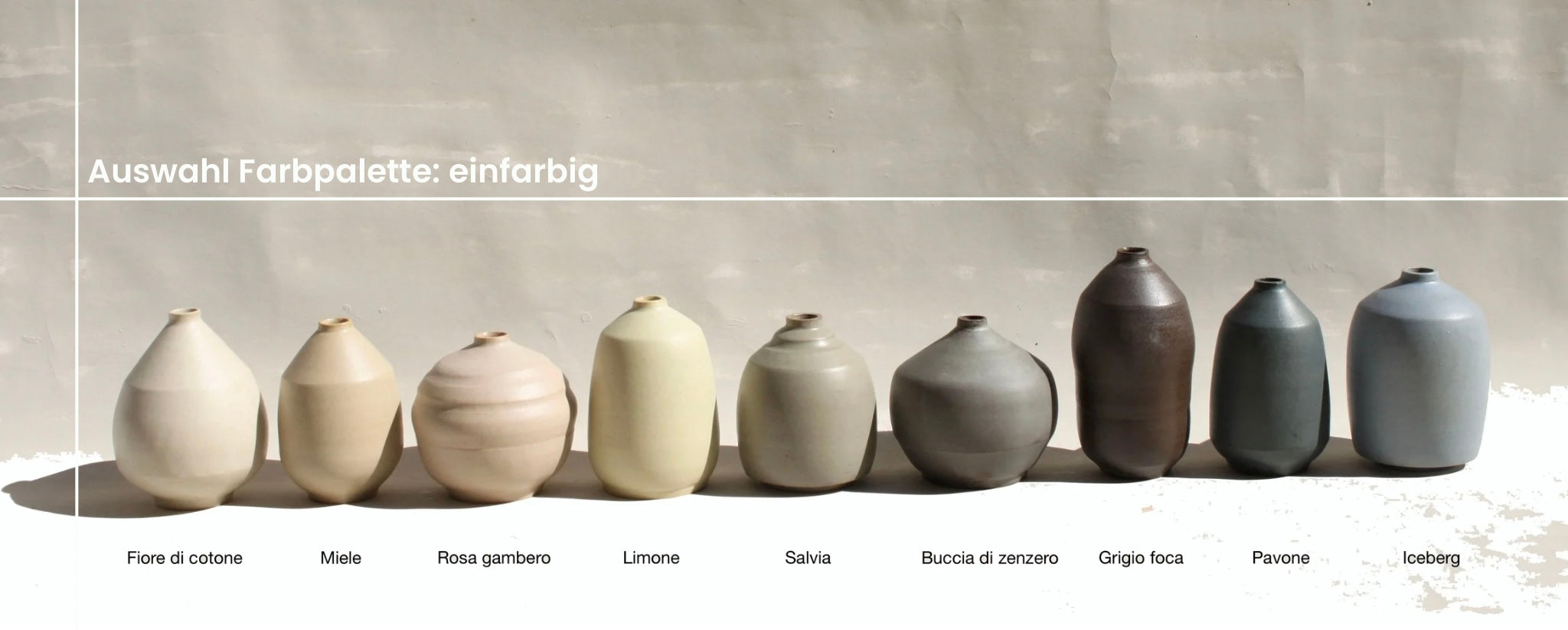 Alle Töne des farbigen Tons sind als Vasen nebeneinander aufgereiht. Von links nach rechts: fiore die cotone, miele, rosa gambero, limone, salvia, buccia di zenzero, grigio foca, pavone, iceberg.