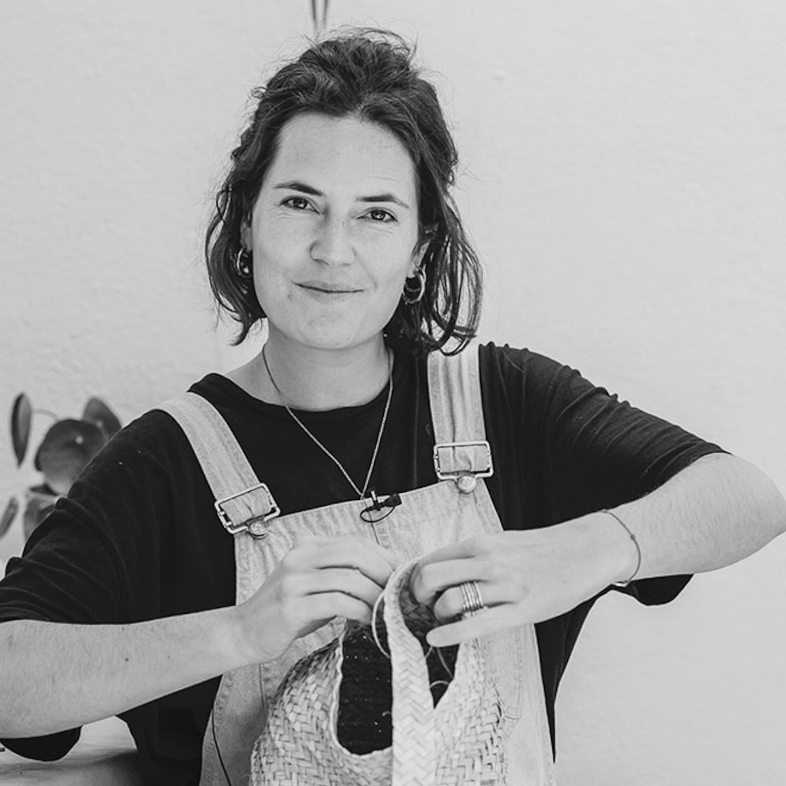 Die Künstlerin Ysaline Ophoff sitzt aug einer Terasse unf fliecgtet an einem Korb.