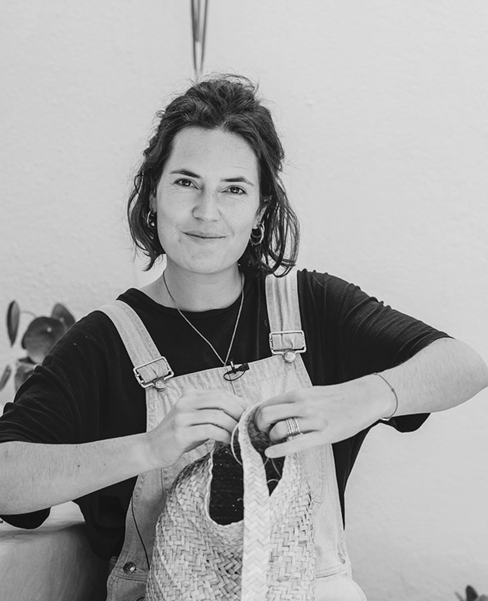 Die Künstlerin Ysaline Ophoff sitzt aug einer Terasse unf fliecgtet an einem Korb.