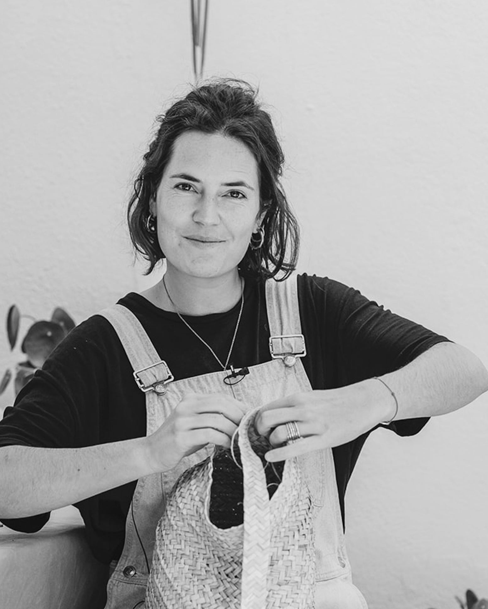 Die Künstlerin Ysaline Ophoff sitzt aug einer Terasse unf fliecgtet an einem Korb.