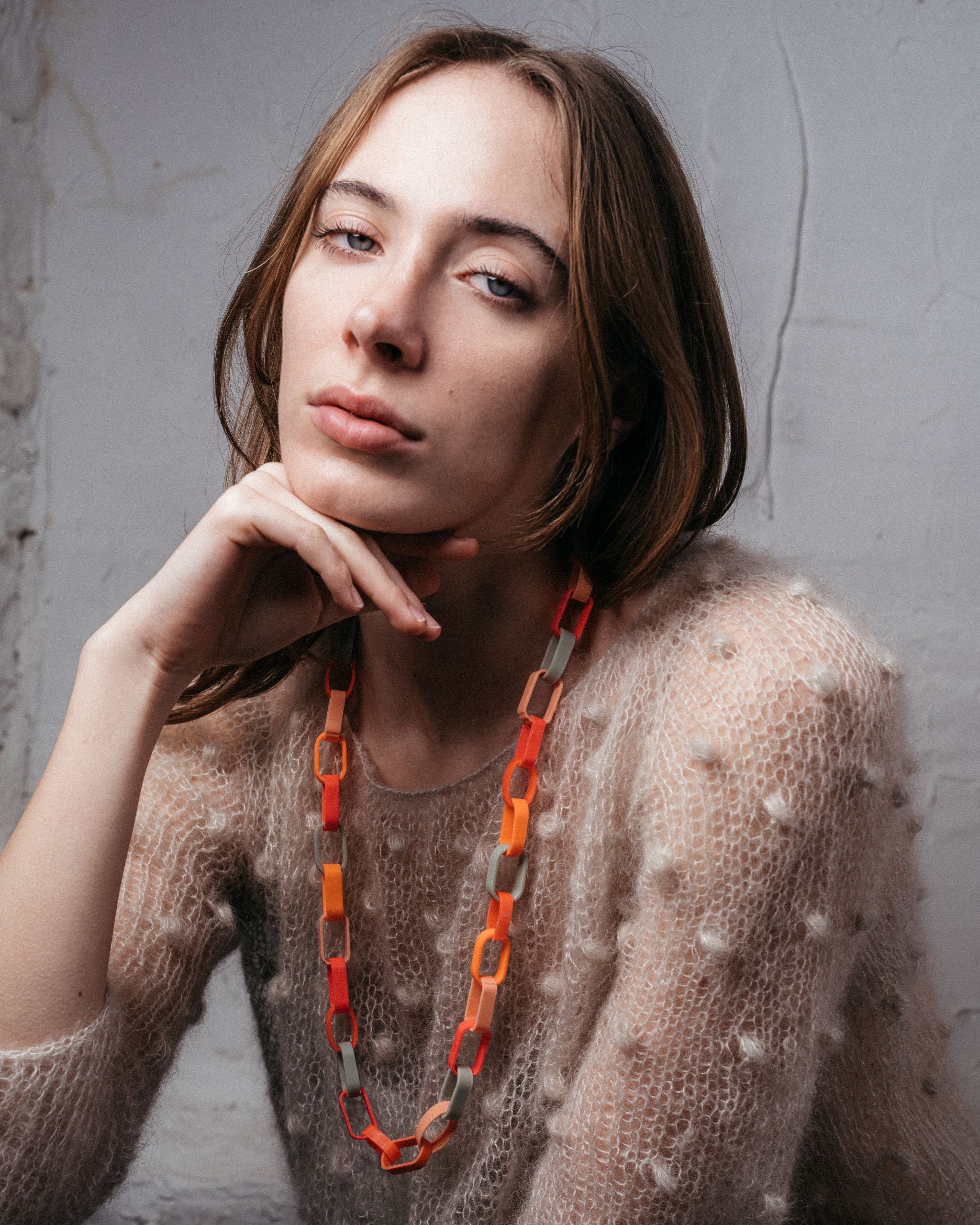 Ein Model trägt eine Gliederkette der Schmuckdesignerin Carla Movia, deren große Glieder in herbstlich leuchtenden Farben aus recyclten Hülsen von Textmarkern bestehen.