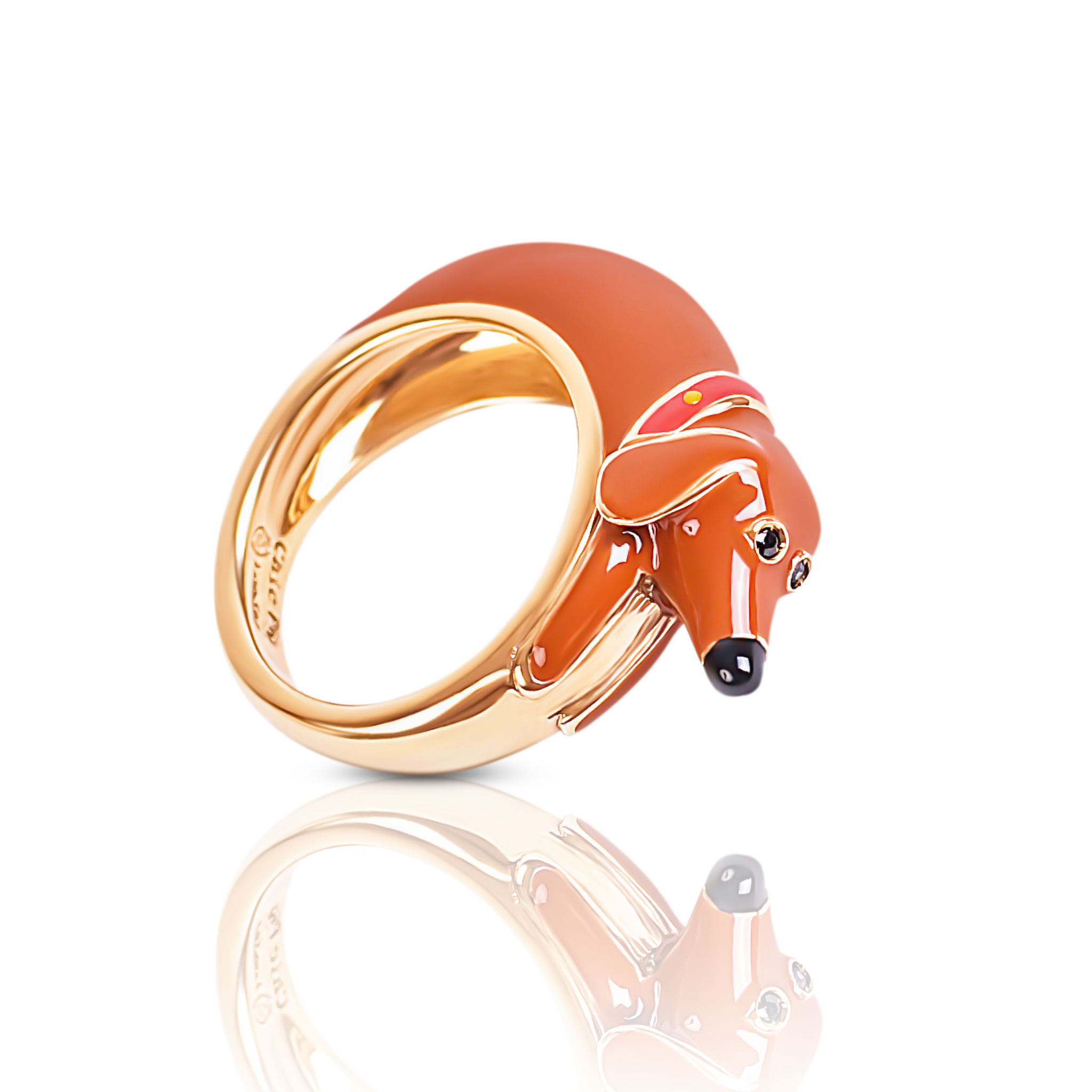 Ein Fingerring der italienischen Schmuckdesignerin Chiara Bello in Form eine braunen Dackels mit rotem Halsband, schwarzer Schnauze, goldenen Konturen und schwarzen Steinchen als Augen.