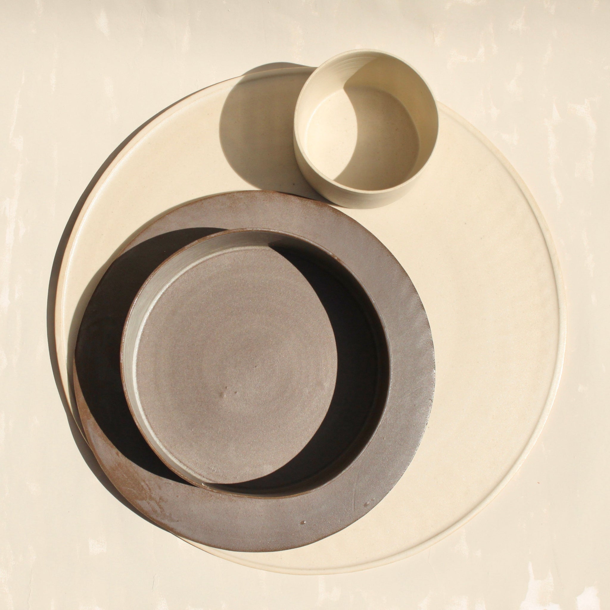 Ein modulares Set der handgefertigten Steingut-Kollektion ROSA MORADA der Genueser Künstlerin Martina Geroni, bestehende aus einem grossemn Pizzateller/Platzset, einem Suppenteller/einer Schale und einem Becher.