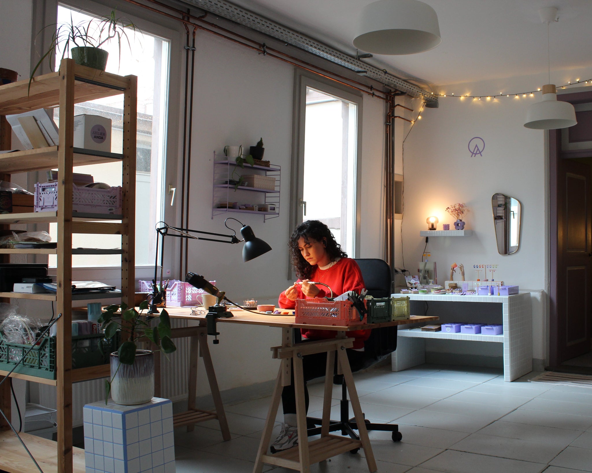 Schmuckdesignerin Alexandra Schütz arbeitet an ihrem Werktisch in ihrem Atelier, umgeben von Werkzeugen, Materialien und fertigen Schmuckstücken.