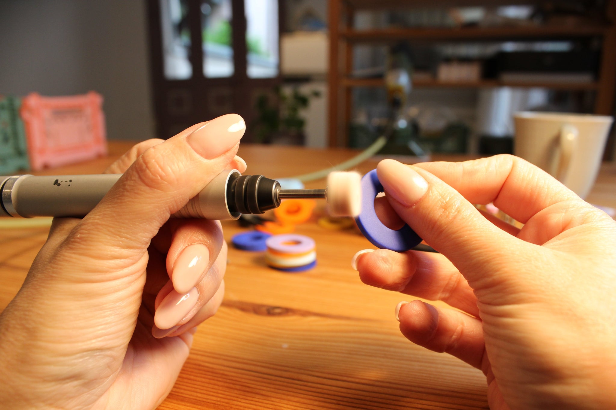 Schmuckdesignerin Alexandra Schütz poliert ein fliederfarbenes Schmuckelement aus Polymerton mit einem Dremel in ihrem Atelier.