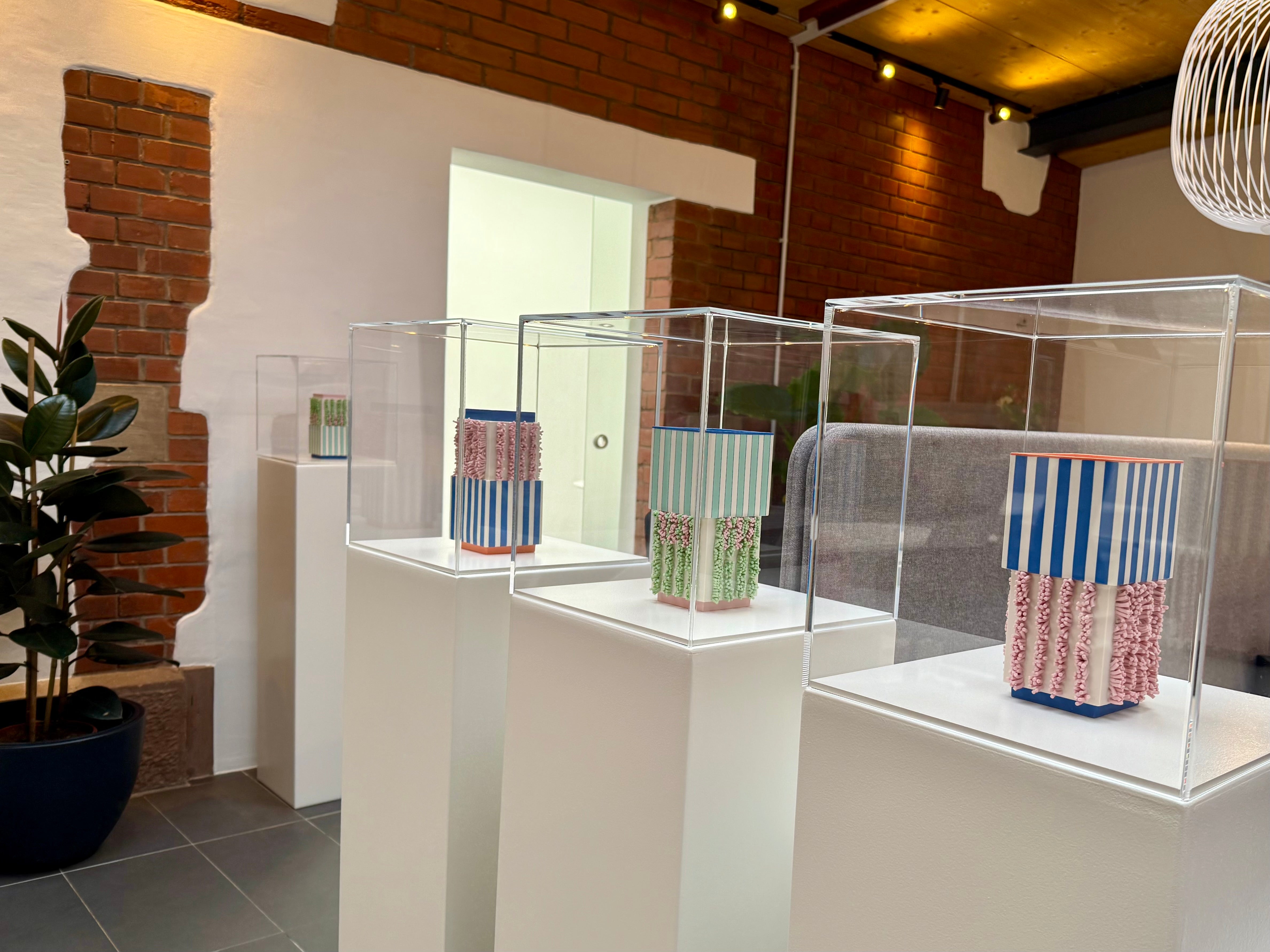 Der Ausstellungsraum im Coworking Zasius, Freiburg, mit vier Galeriesockeln auf denen Porzellanvasen von Jungwoon Lee stehen.