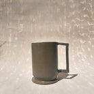 Eine Kermiktasse mit rechteckigem Henkel und Deckel, der zugleich Untersetzer ist, hergestellt von der genueser Künstlerin Martina Geroni.