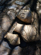 Handgeflochtene Wandskulptur CARRIERS von Ysaline Ophoff: drei organisch geformte Module aus Palmwedeln und Esparto-Gras, mit spiralartigen Reliefs, liegend auf Naturstein und im Spiel von Licht und Schatten fotografiert.