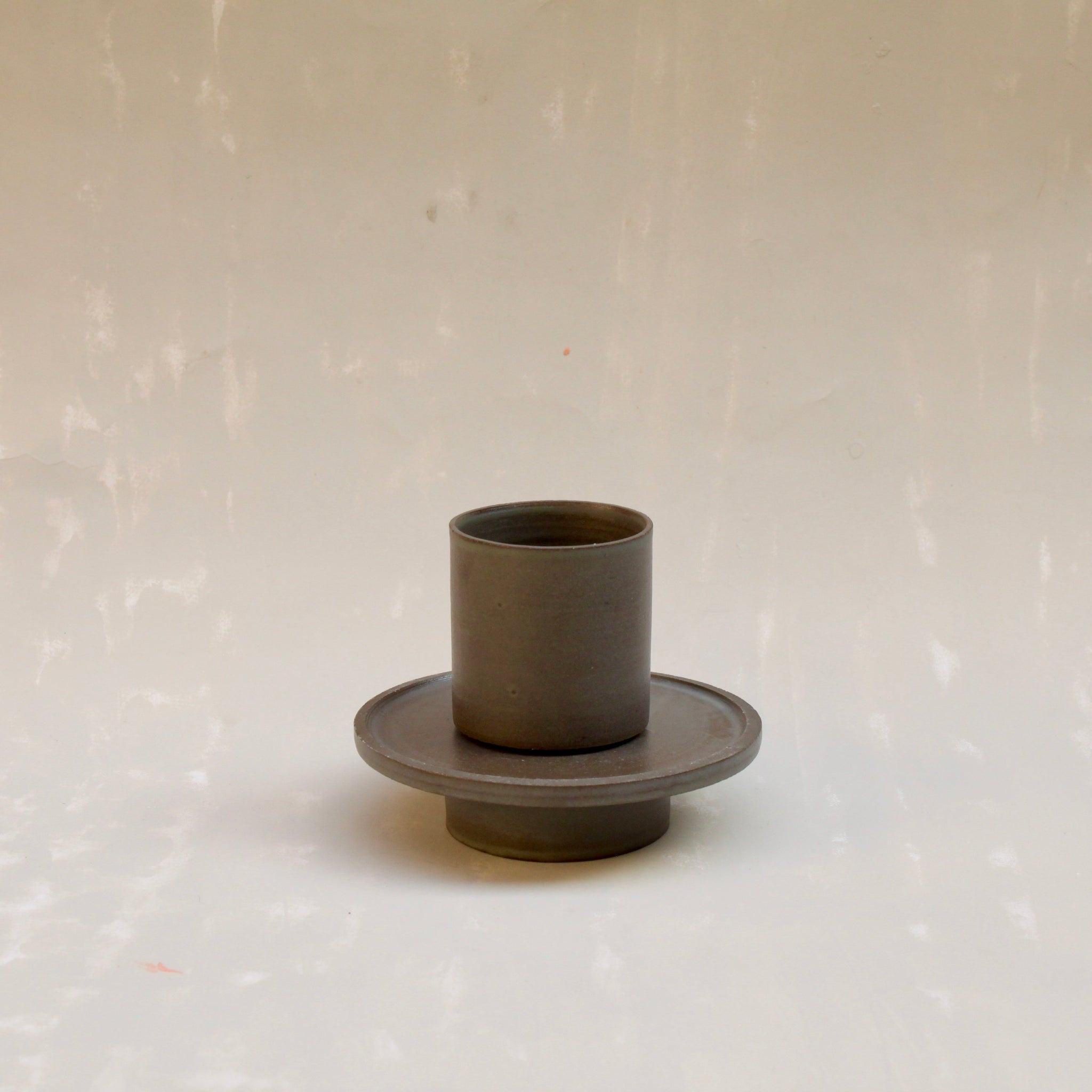 Modularer Espressobecher mit Untertasse aus der Kollektion ROSA MORADA von Martina Geroni in der Tonfarbe Buccia di Zenzero, gezeigt mit aufgesetztem Becher auf der leicht erhöhten, scheibenförmigen Untertasse aus handgefertigtem Steingut.