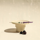 Modularer Espressobecher mit Schälchen aus der Kollektion ROSA MORADA von Martina Geroni in der Tonfarbe Fiore di Cotone, handgefertigt aus Steingut, als kleine erhöhte Platte arrangiert, mit Lavendelzweig und Brombeeren.