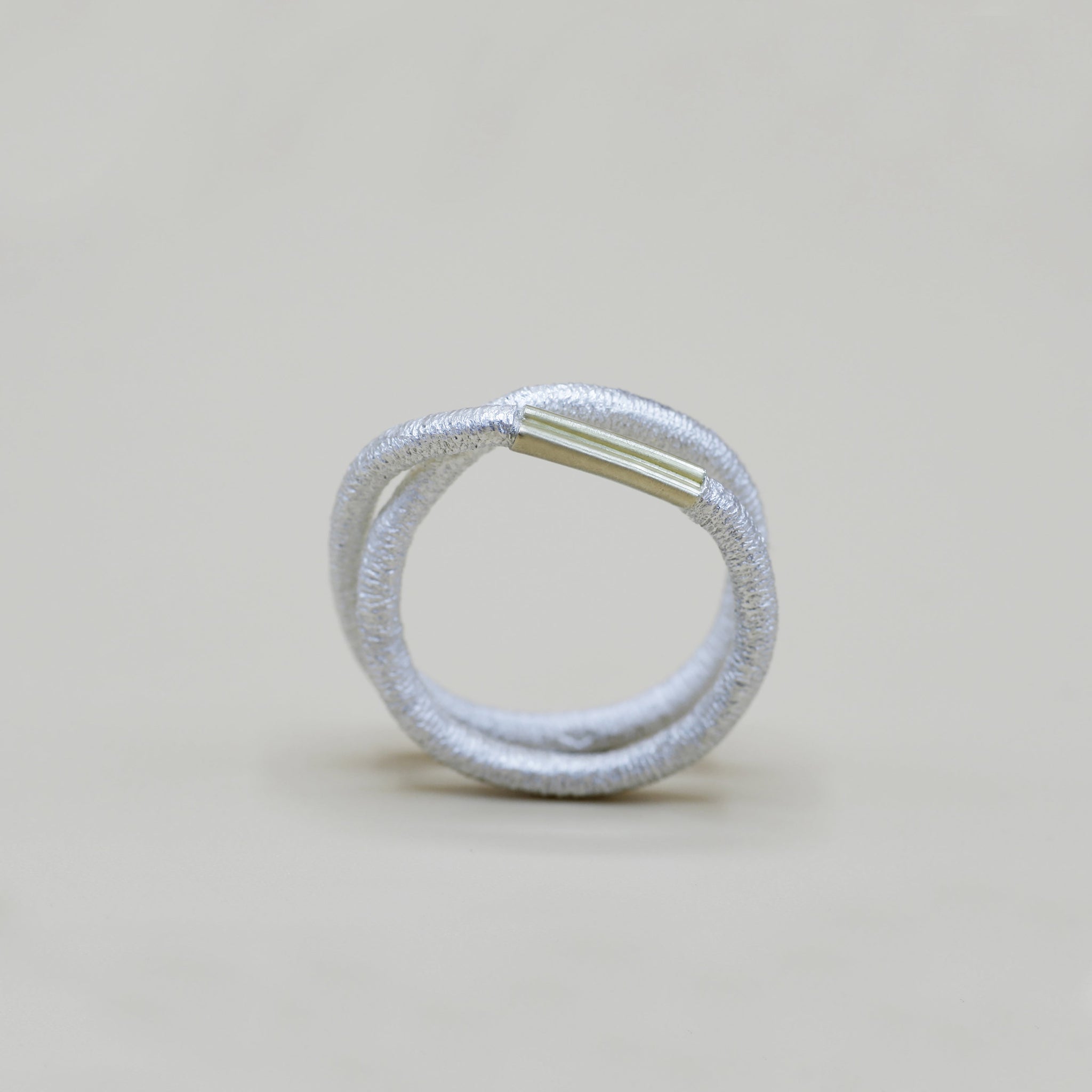 Ein silberner Fingerring, der aussieht wie ein Haargummi, den man sich um den Finger wickelt - gefertigt von der Straßburger Goldschmiedin Annie Sibert.