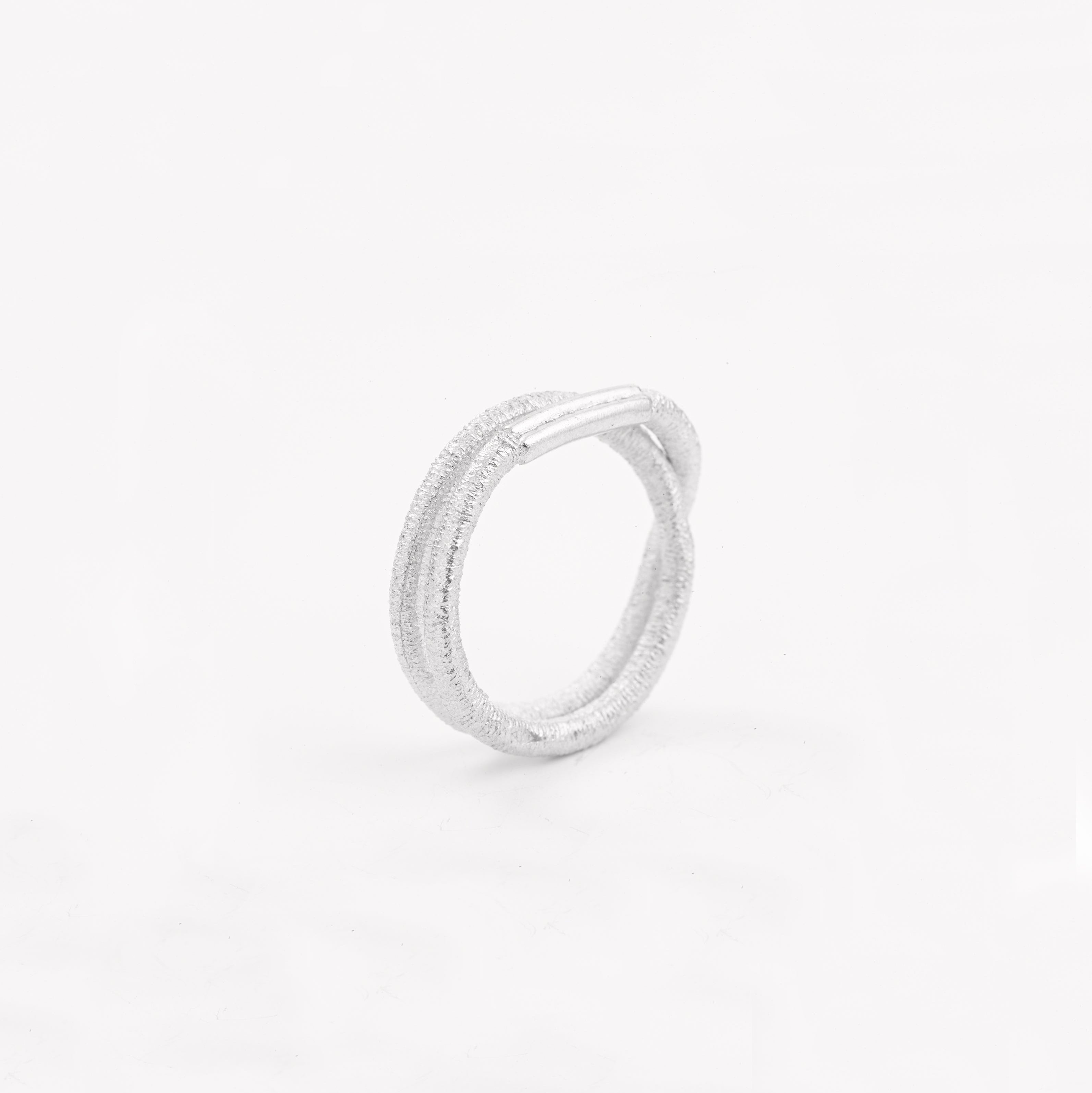 Ein silberner Fingerring, der aussieht wie ein Haargummi, den man sich um den Finger wickelt - gefertigt von der Straßburger Goldschmiedin Annie Sibert.