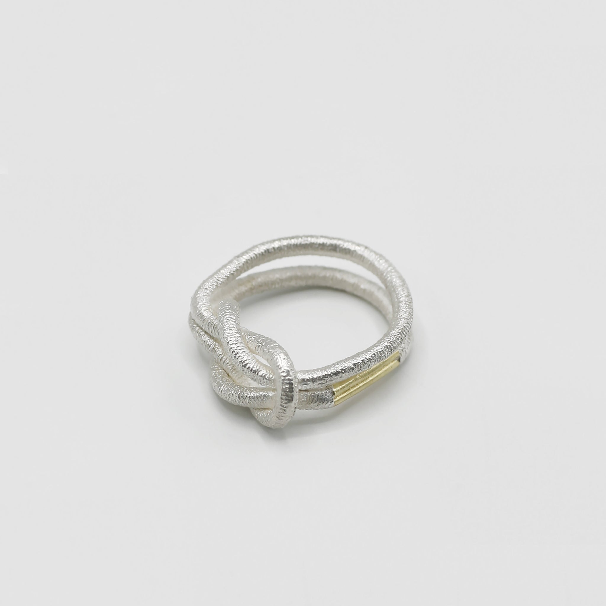 Ein silberner Fingerring, der aussieht wie ein verknotetes, dünes Haargummi - gefertigt von der französischen Goldschmiedin Annie Sibert.