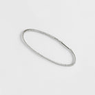 Ein Drei-Finger-Ring, der aussieht, wie ein dünnes Haargummi, das man über drei Finger spannt - hergestellt von Goldschmiedin Annie Sibert.