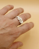 Ein Drei-Finger-Ring, der aussieht, wie ein dünnes Haargummi, das man über drei Finger spannt - hergestellt von Goldschmiedin Annie Sibert.