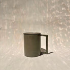 Eine Kermiktasse mit rechteckigem Henkel und Deckel, der zugleich Untersetzer ist, hergestellt von der genueser Künstlerin Martina Geroni.