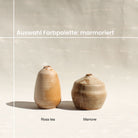 Alle Töne des farbigen Tons sind als Vasen nebeneinander aufgereiht. Von links nach rechts: fiore die cotone, miele, rosa gambero, limone, salvia, buccia di zenzero, grigio foca, pavone, iceberg.