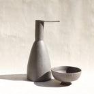 Eine Keramikkaraffe in Form eines stilisierten Reihers, mit einem abnehmbaren Schälchen als Fuss.