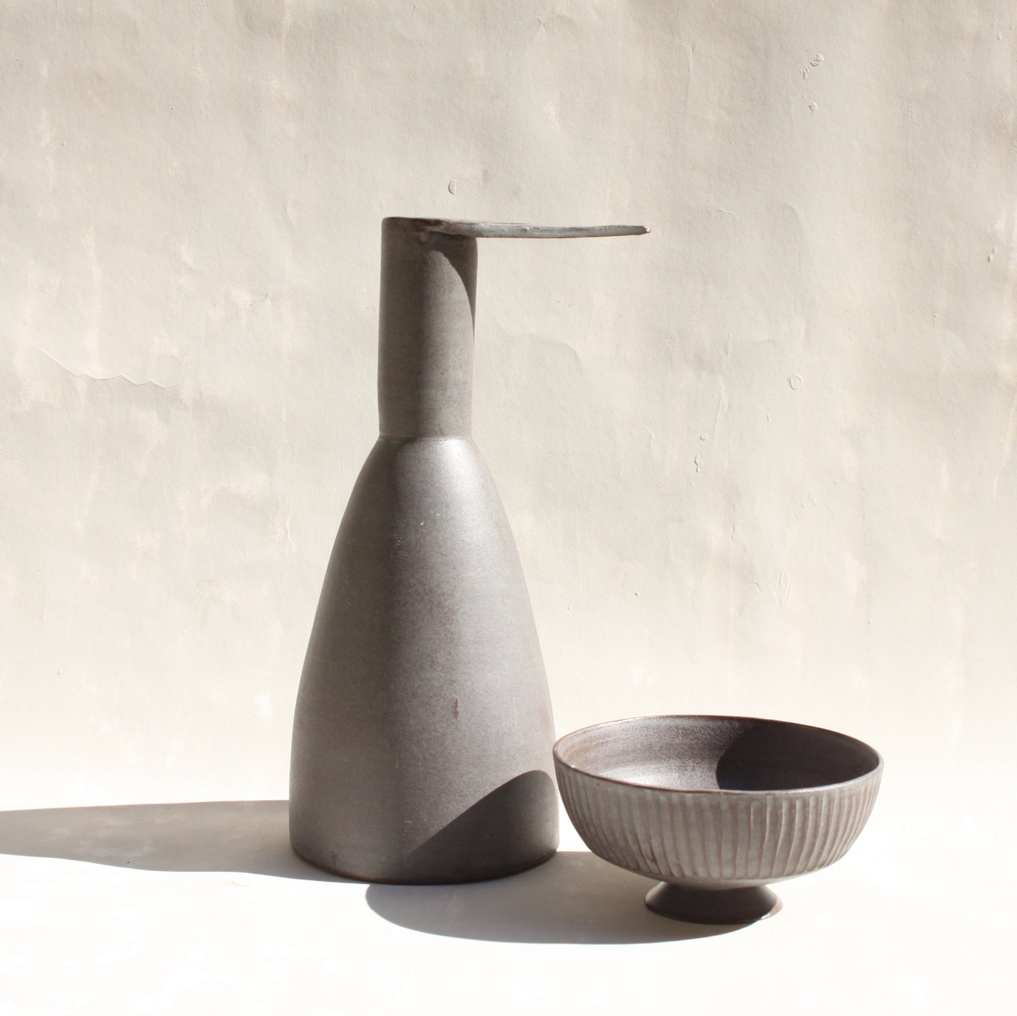 Eine Keramikkaraffe in Form eines stilisierten Reihers, mit einem abnehmbaren Schälchen als Fuss.