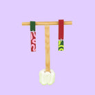 Asymmetrische Ohrringe aus Polymerton mit schmalen rechteckigen Elementen und grafischen Mustern in Rot, Rosa, Grün und Neongelb, präsentiert auf einem hölzernen Schmuckständer.