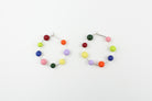 Handgefertigte Statement-Creolen aus Silber mit jeweils acht bunten Polymerton-Kugeln, präsentiert auf einem Holzständer vor hellem Hintergrund.