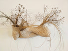 Wandskulptur PALMA VI von Ysaline Ophoff (atelier balancê): horizontales, handgeflochtenes Objekt in Form einer breiten Tasche aus getrockneten Palmblättern, die in drei  taschenartigen Module unterteilt ist und die an der Wand befestigt sind . Mit getrockneten Pflanzen bestückt. 