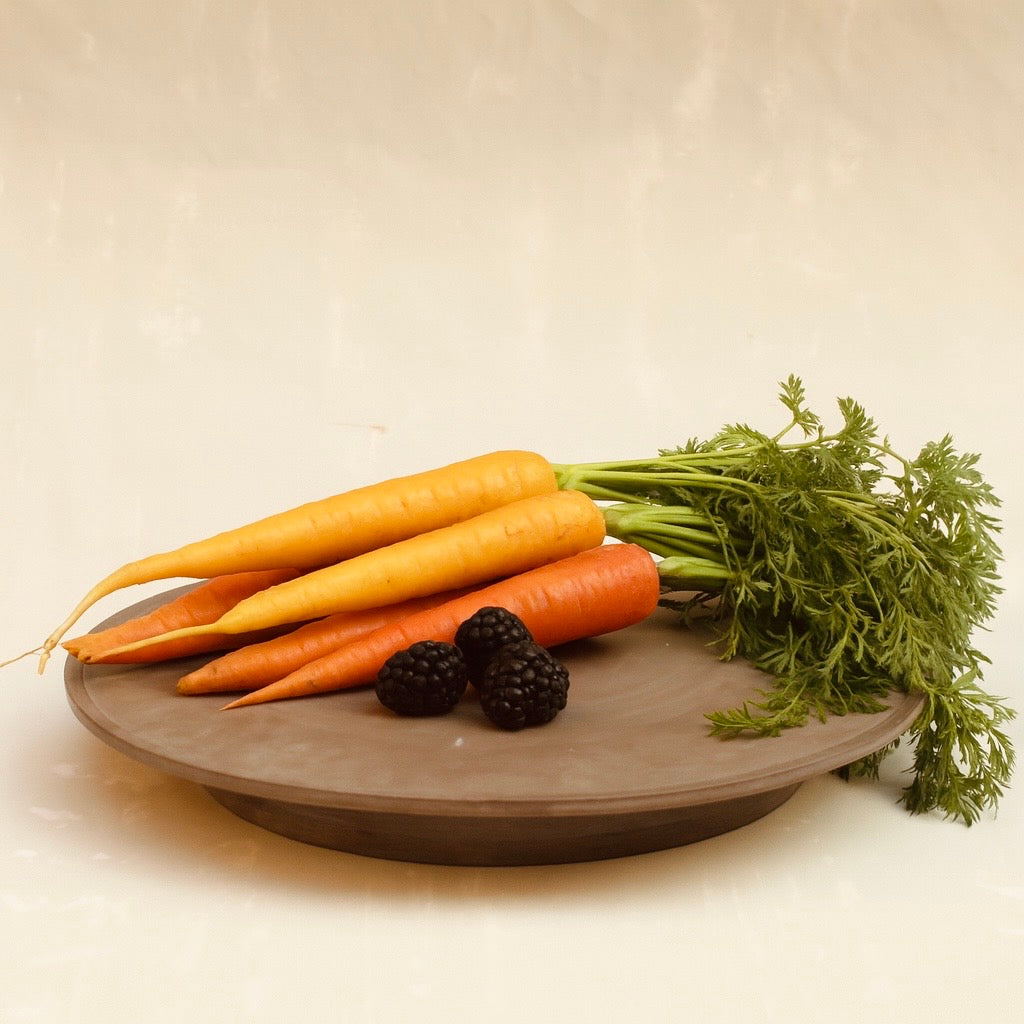 Große Platte aus der Kollektion ROSA MORADA von Martina Geroni in der Tonfarbe Buccia di Zenzero, flach liegend gezeigt und arrangiert mit Karotten und Brombeeren, aus handgefertigtem Steingut.